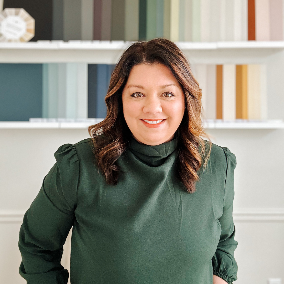 A woman in a green top smiling at the camera with a blend of soft colors in the background.