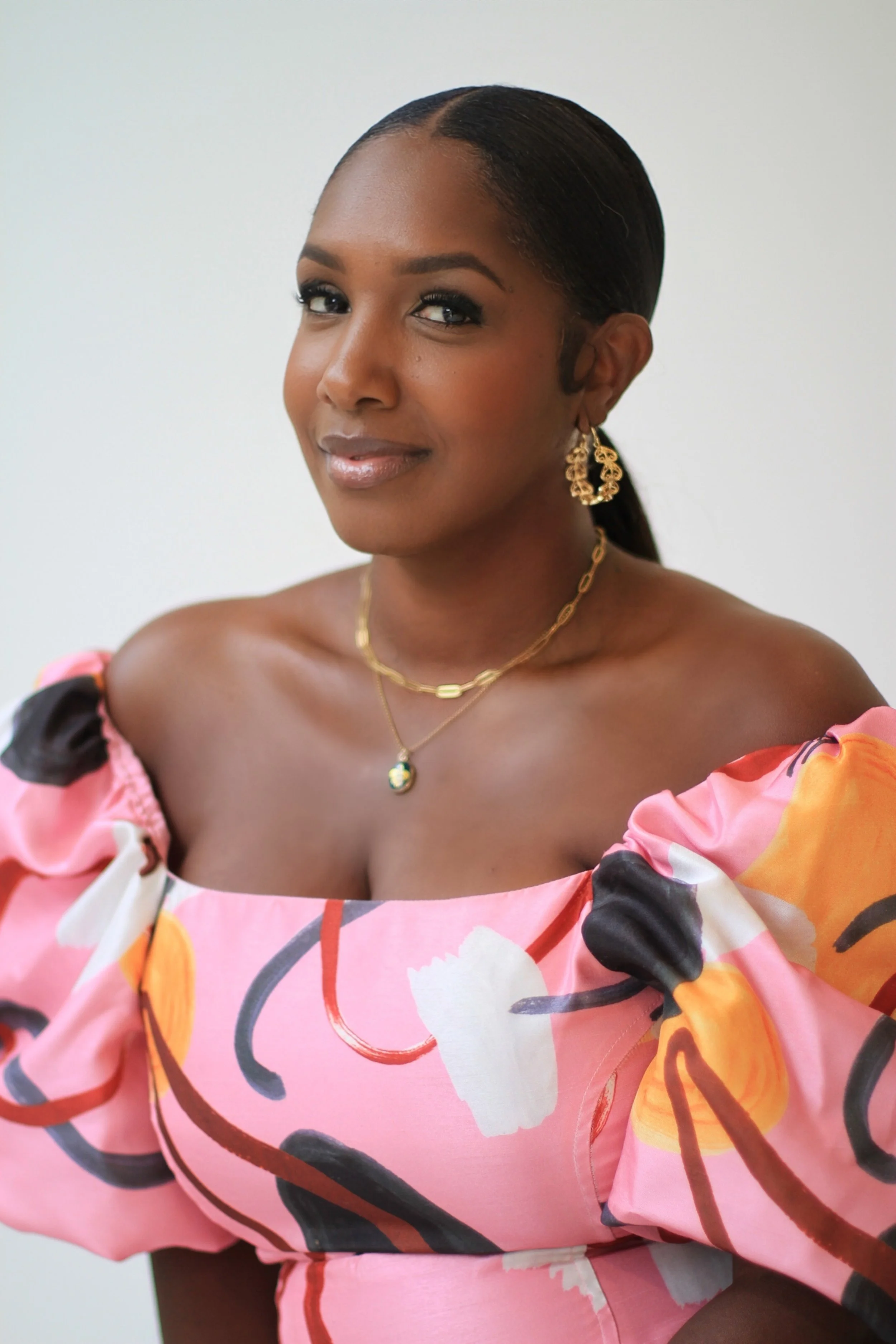 Jamila Crawford Pécou, cultural architect and luxury travel coordinator, posing confidently in an elegant floral gown- the face behind EARTHCANDY ARTS and the rē retreat experience.