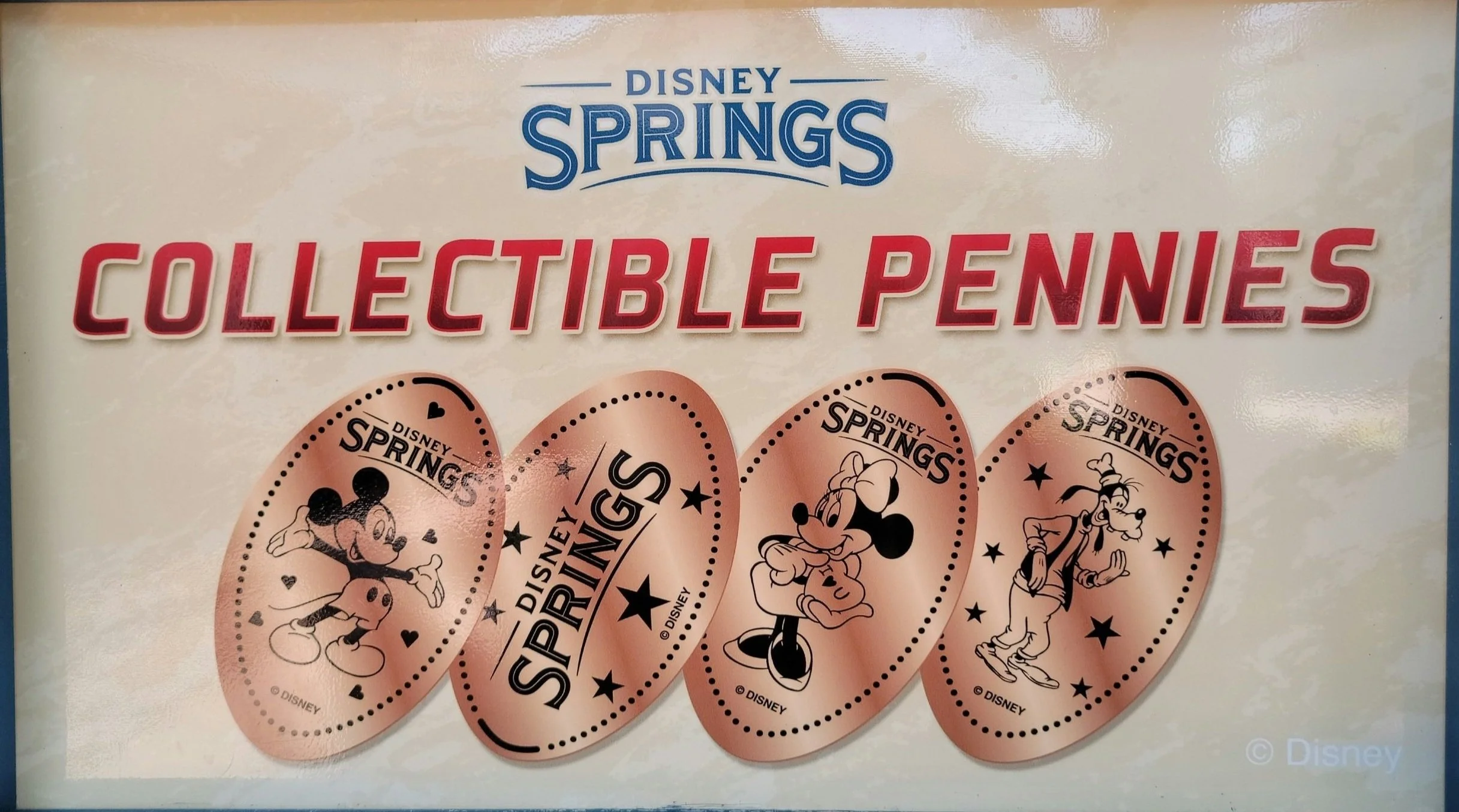 Sign showcasing collectible pressed pennies available at Disney Springs