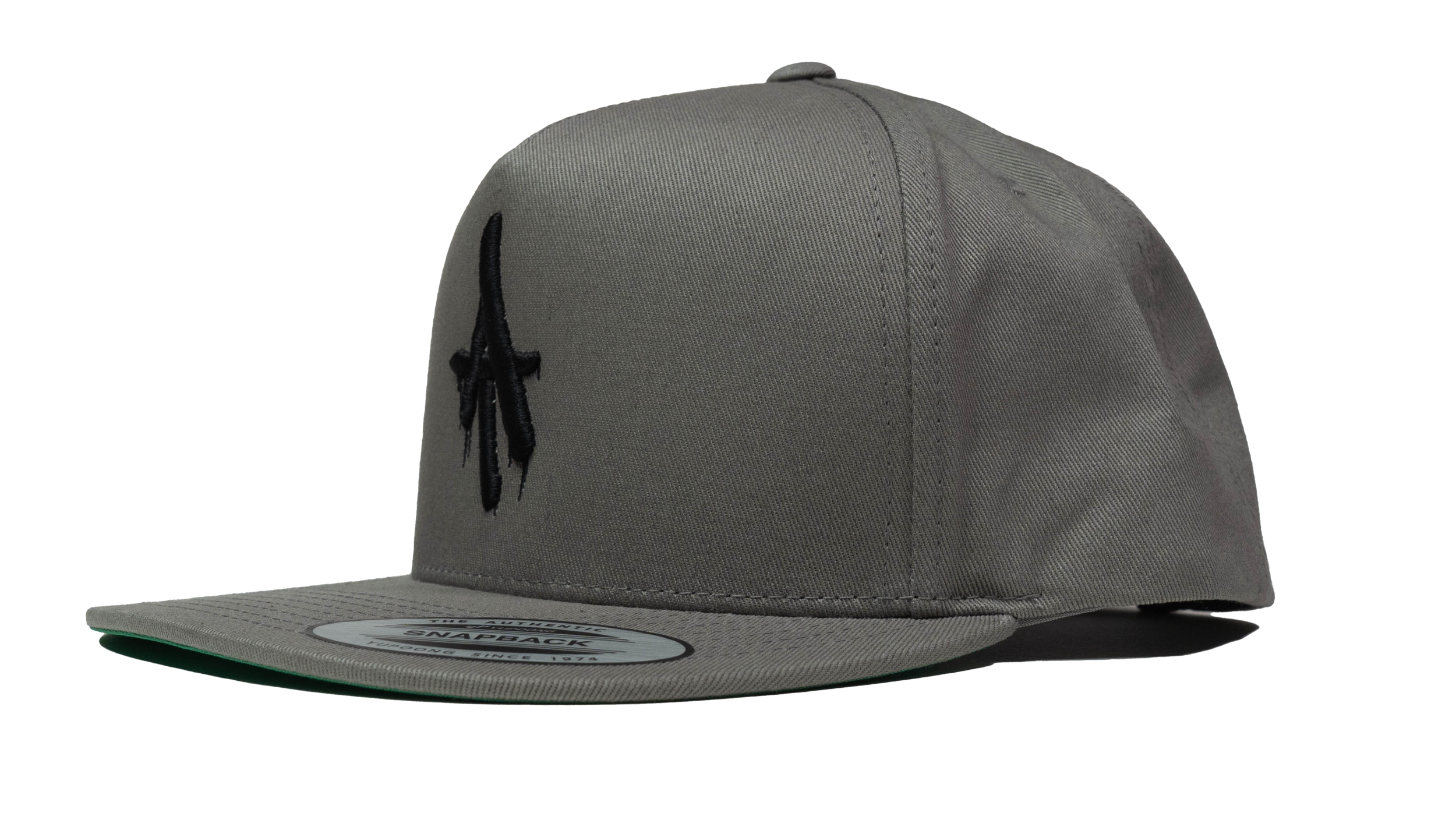 Side view of a gray flat-bill snapback hat featuring a black embroidered dripping “AT” logo on the front panel.