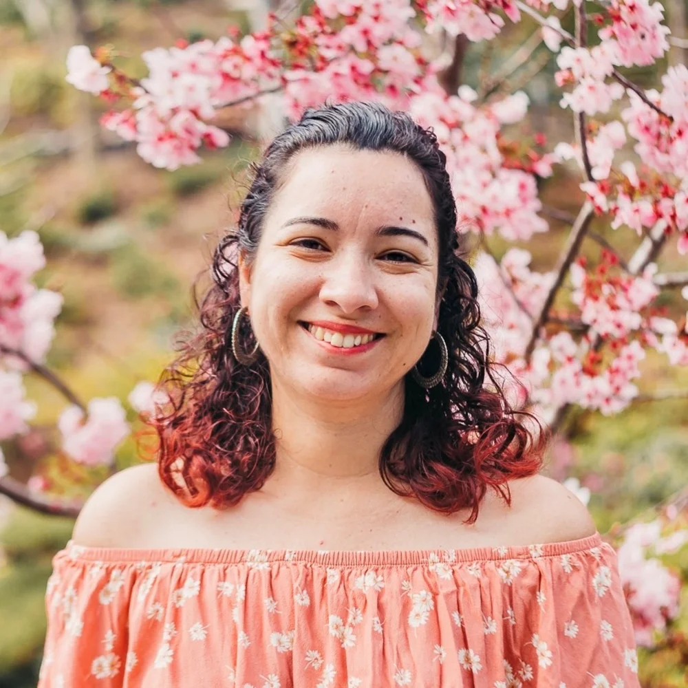 Brianna Coston smiling in front of a blossoming tree