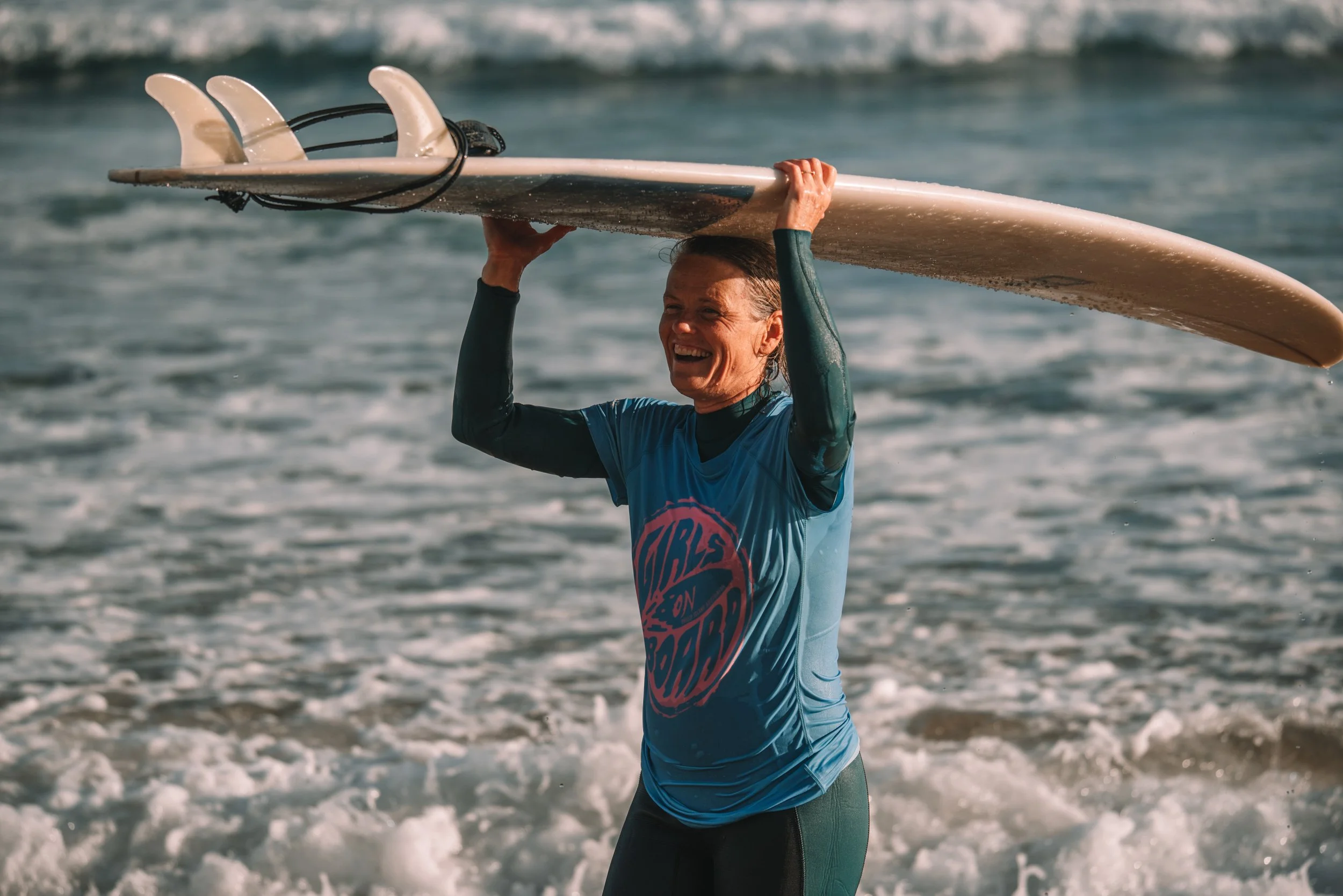 Woman holding surfboard above her head on beach