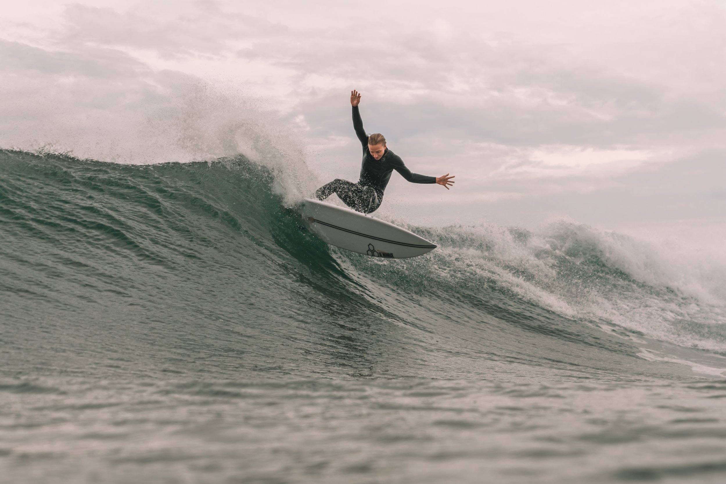 Woman surfing a wave on a cloudy day.