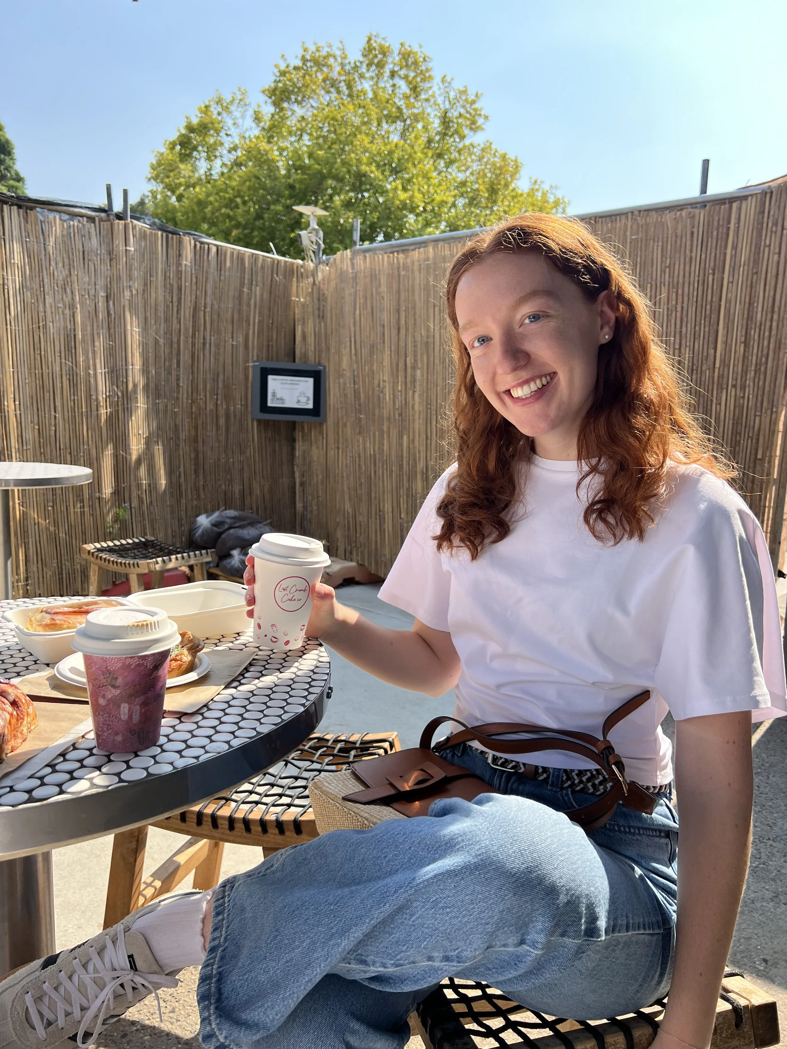 Girl smiling while holding a cup of coffee.