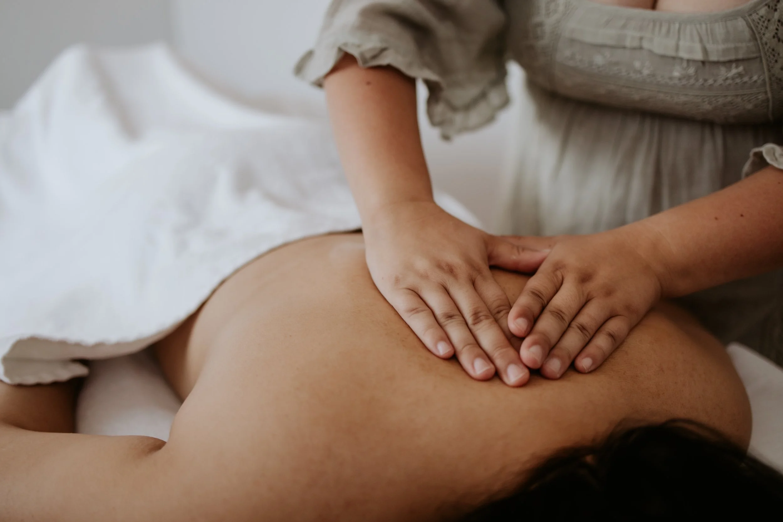 Person receiving a back massage on a massage table covered with a white towel.
