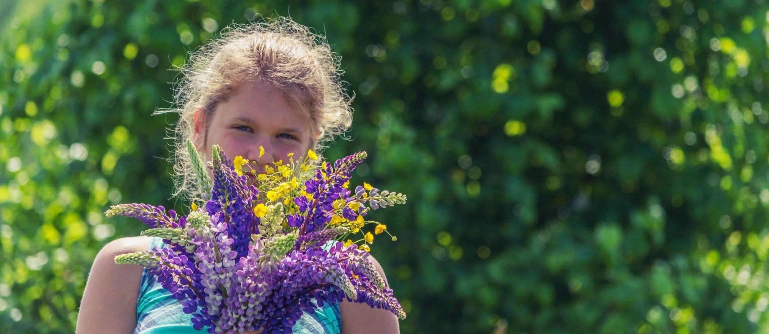Child holding flowers at Naramata Centre in summer