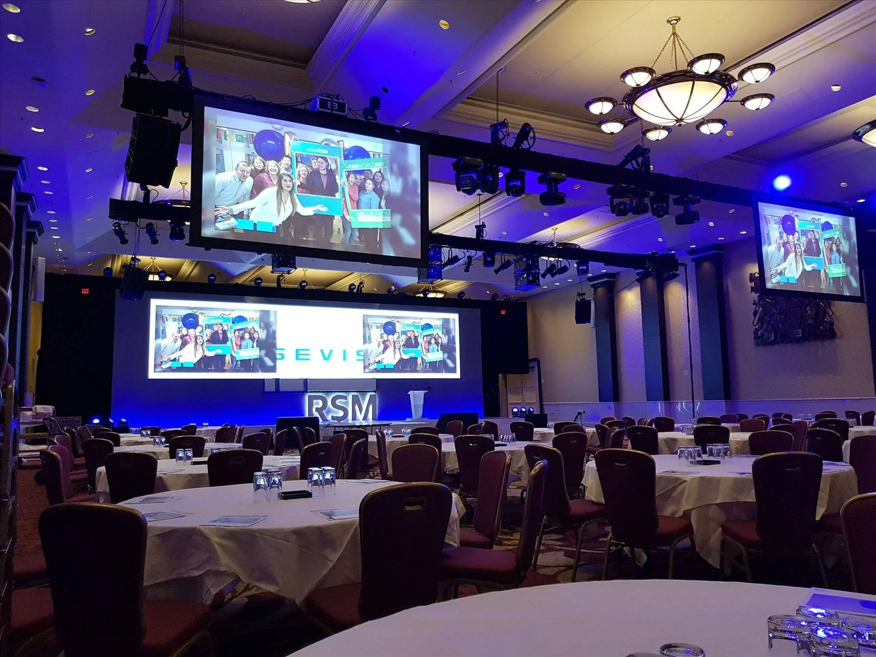 Hotel ballroom set for a conference with stage, screens and chandeliers
