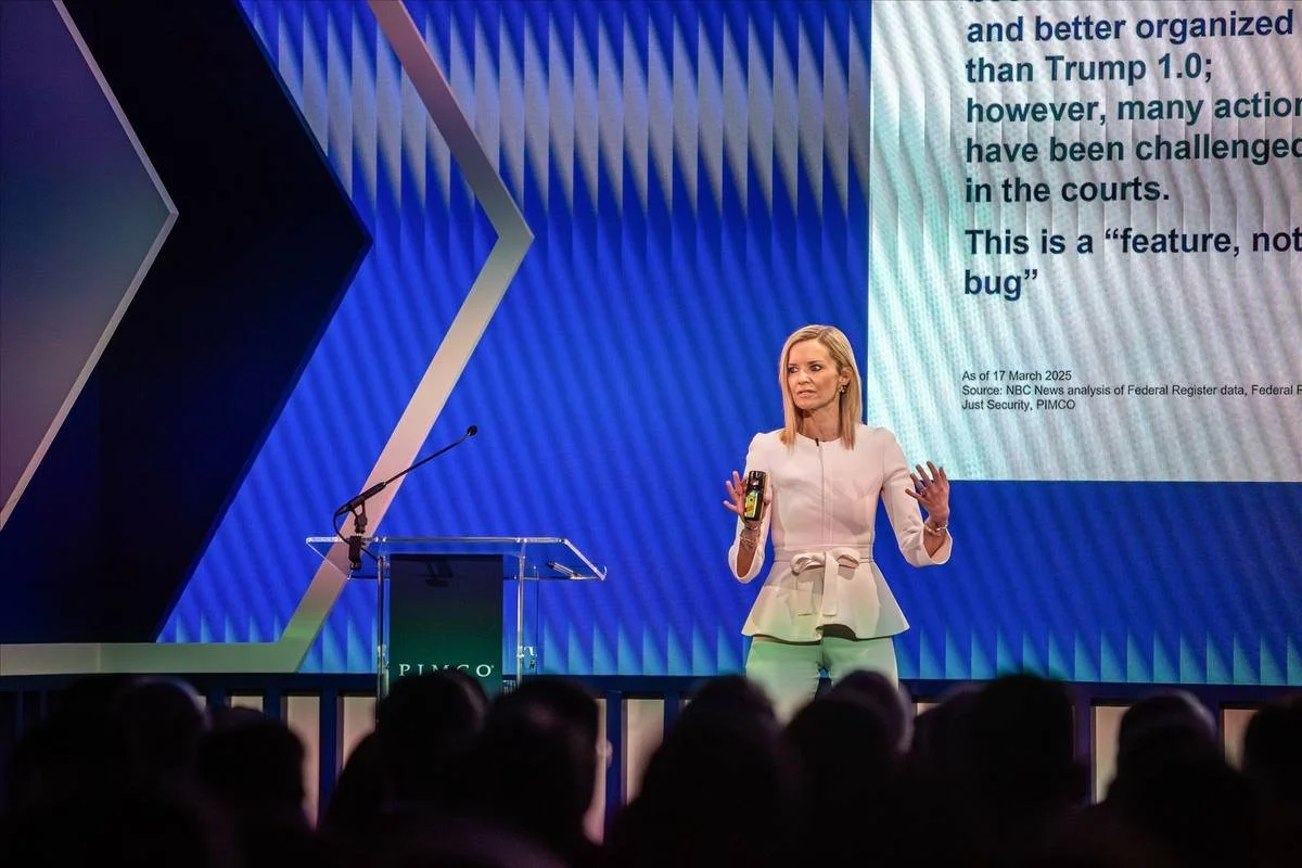 Keynote speaker presenting on stage with presentation content on the screen behind