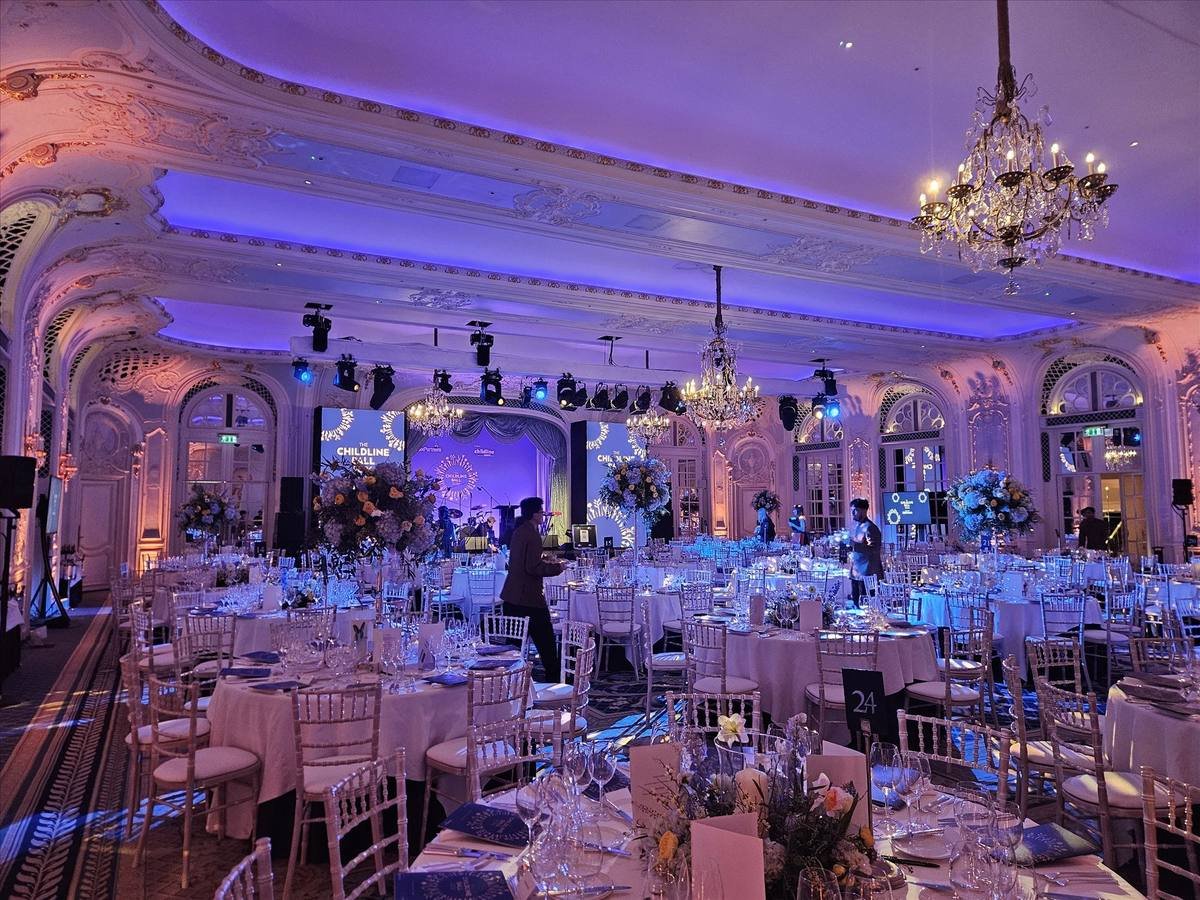 Ballroom dressed for a gala dinner with blue and pink uplighting and chandeliers