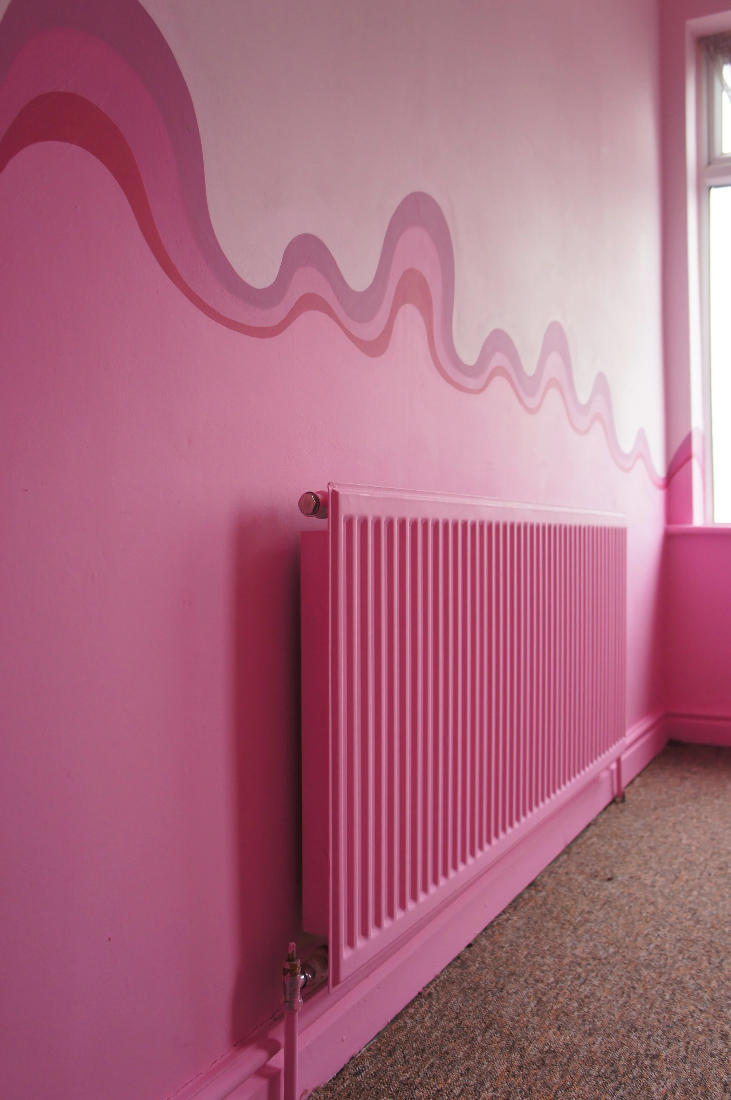A pink radiator in a bedroom with a pink swirly stripe above