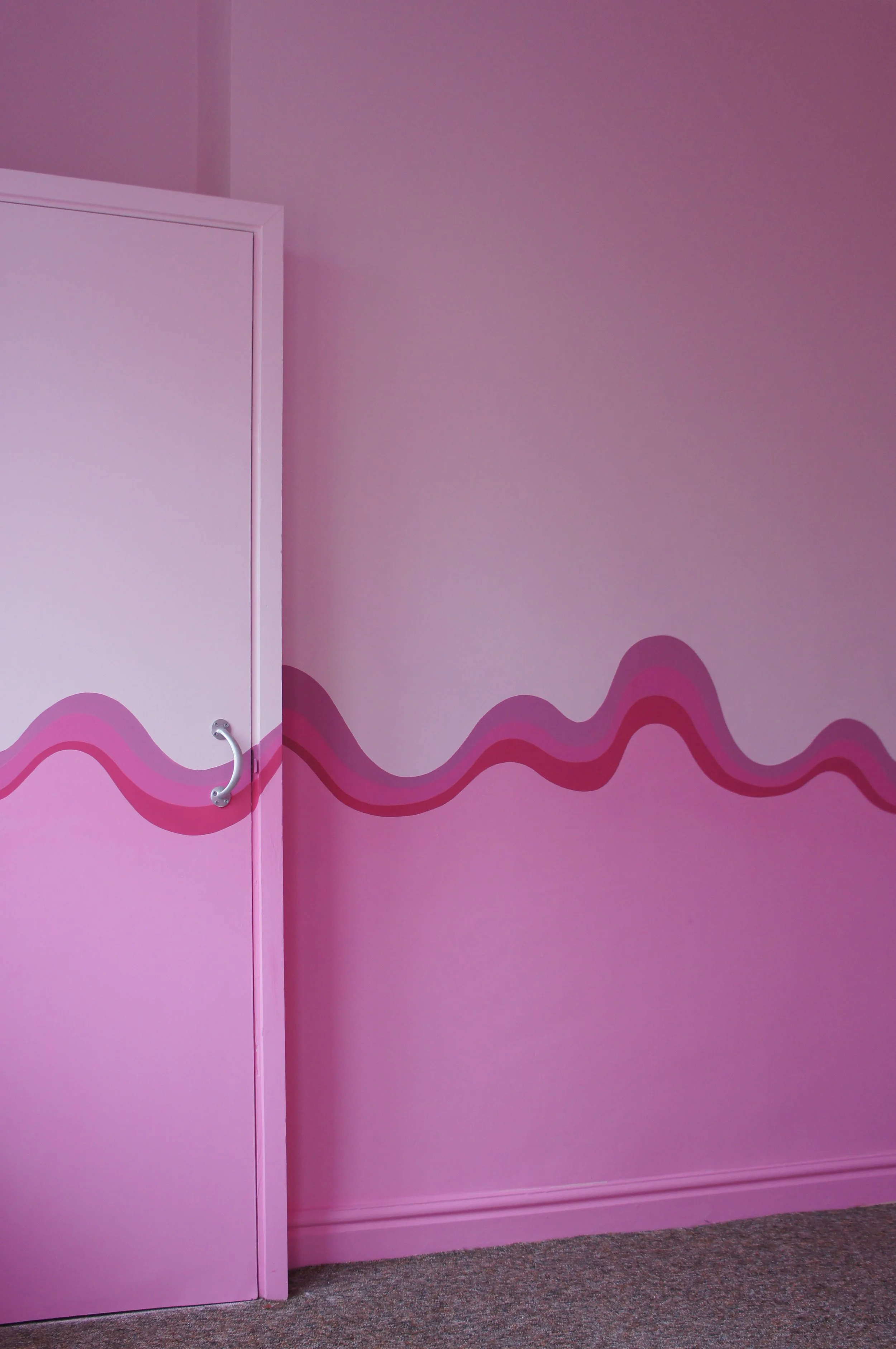 A swirly stripe of shades of pink runs across a bedroom cupboard and chimney breast