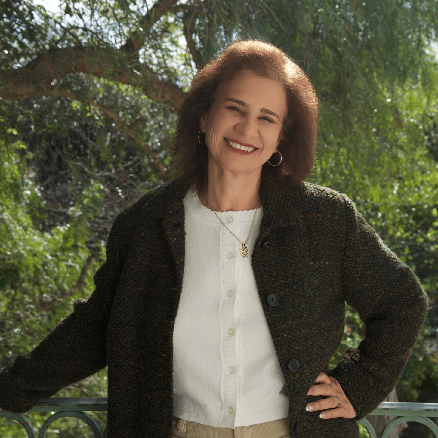 A woman with shoulder-length reddish-brown hair, smiling, wearing a red top against a white background.
