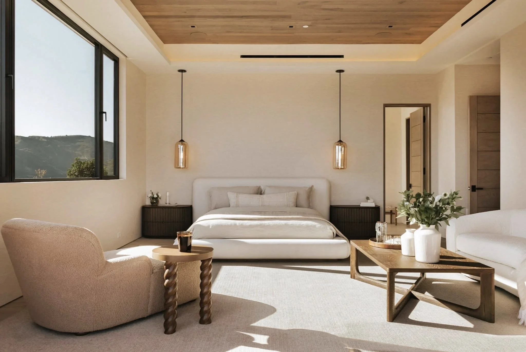 Rachael Goddard Design Studio Calabasas A modern, minimalistic bedroom with a large bed, side tables, hanging pendant lights, a beige armchair with a small round table, a wooden coffee table with vases and a plant, a white sofa,
