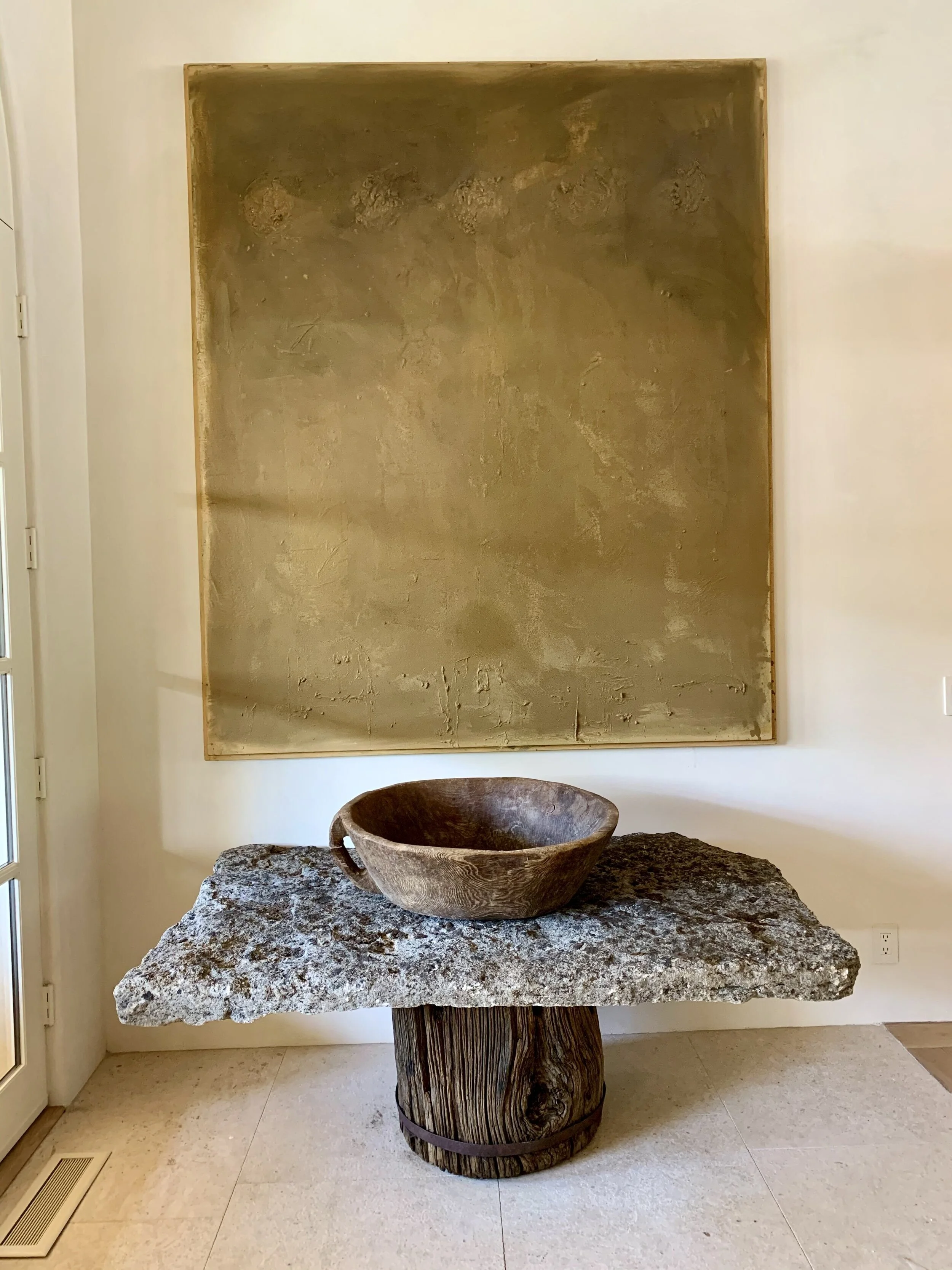 Rachael Goddard Design Studio Malibu Retreat stone console table with rustic wood base, decorative bowl, abstract artwork, and luxury Malibu interiors.