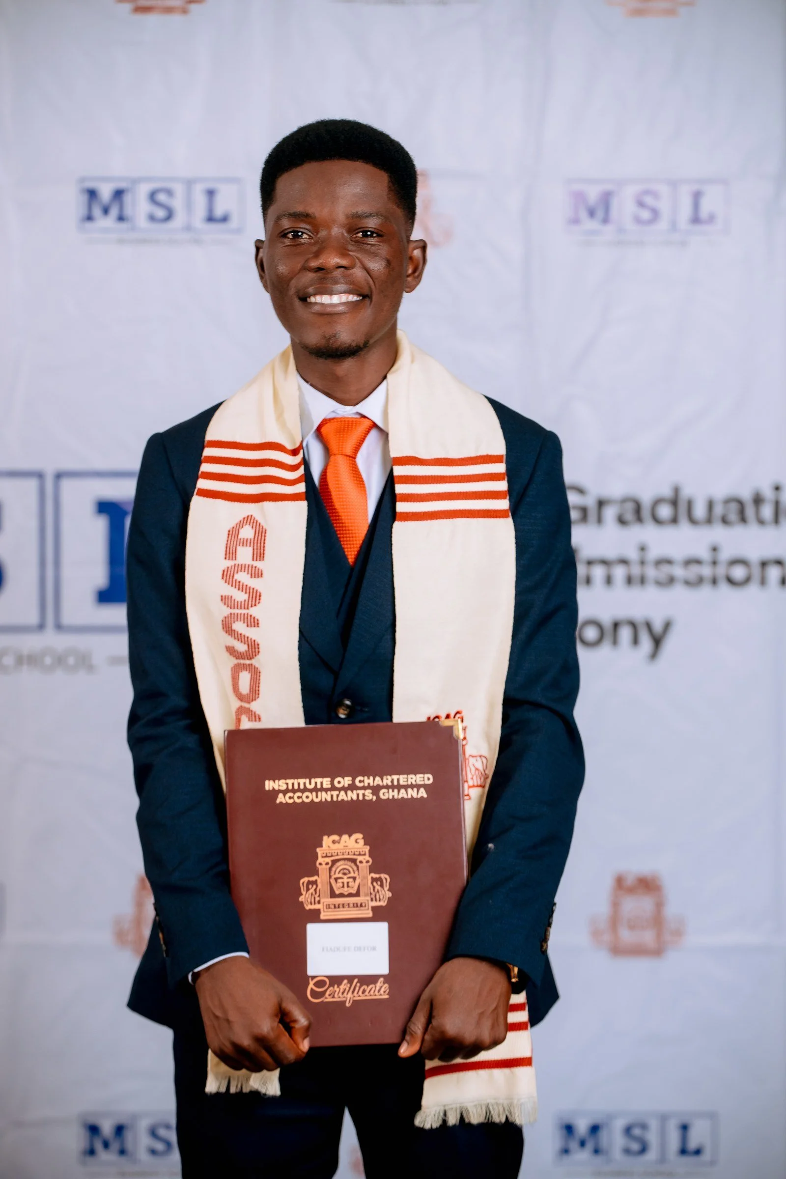 Smiling graduate in a cream ICAG stole holding a certificate folder at the MSL backdrop, ICAG graduation, September 2025.