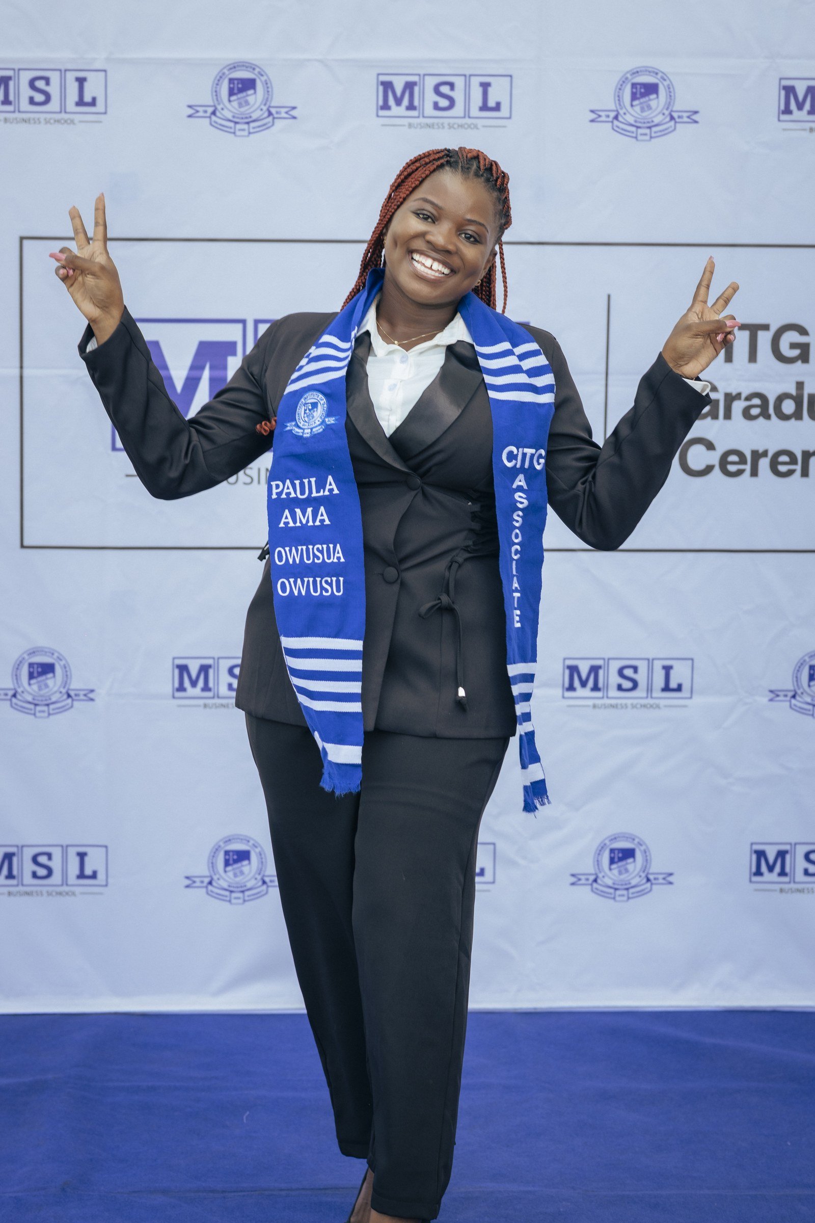 Graduate in a blue CITG stole celebrating with both hands raised, CITG graduation, May 2026.