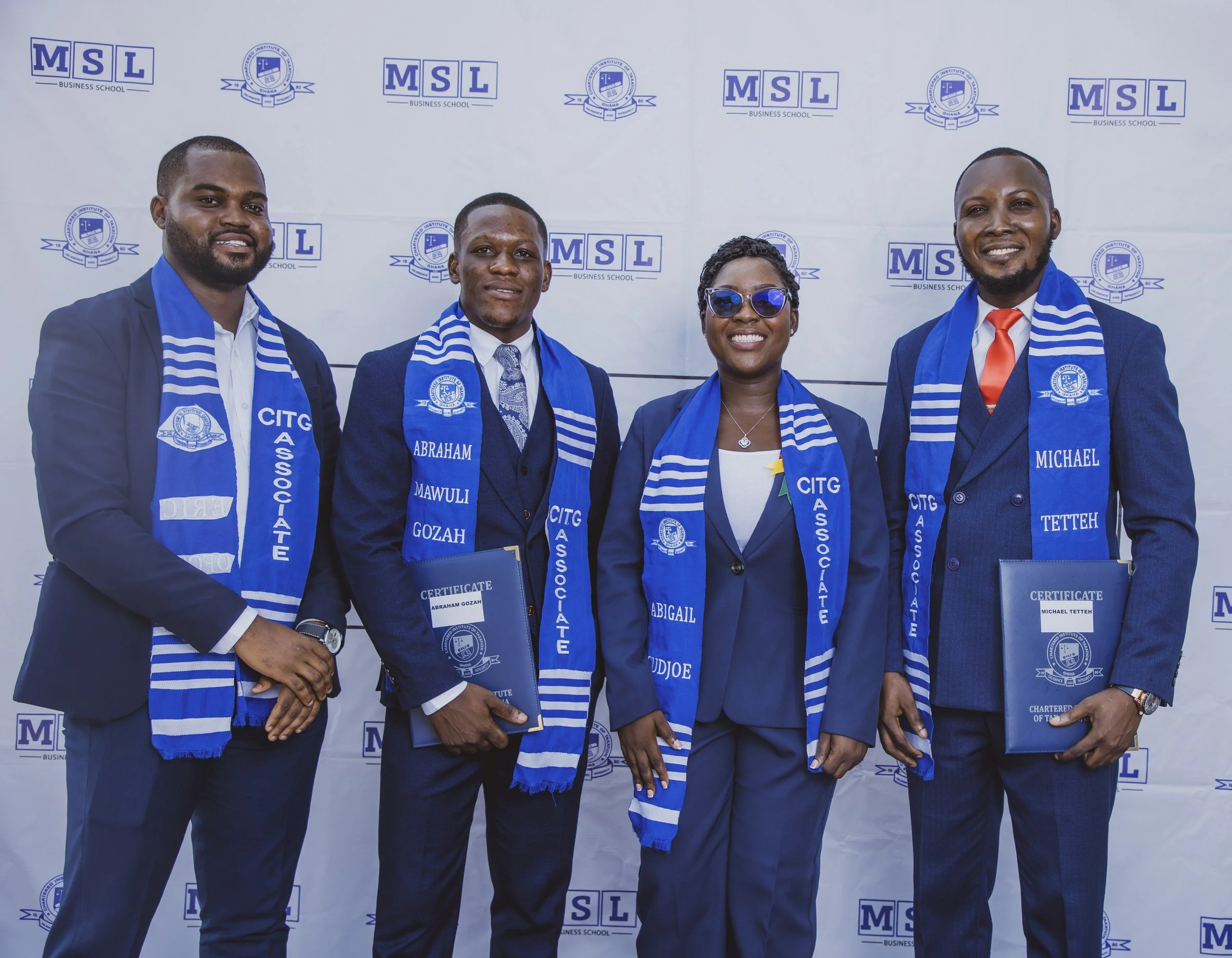Four graduates in blue CITG stoles holding certificate folders together, CITG graduation, May 2026.