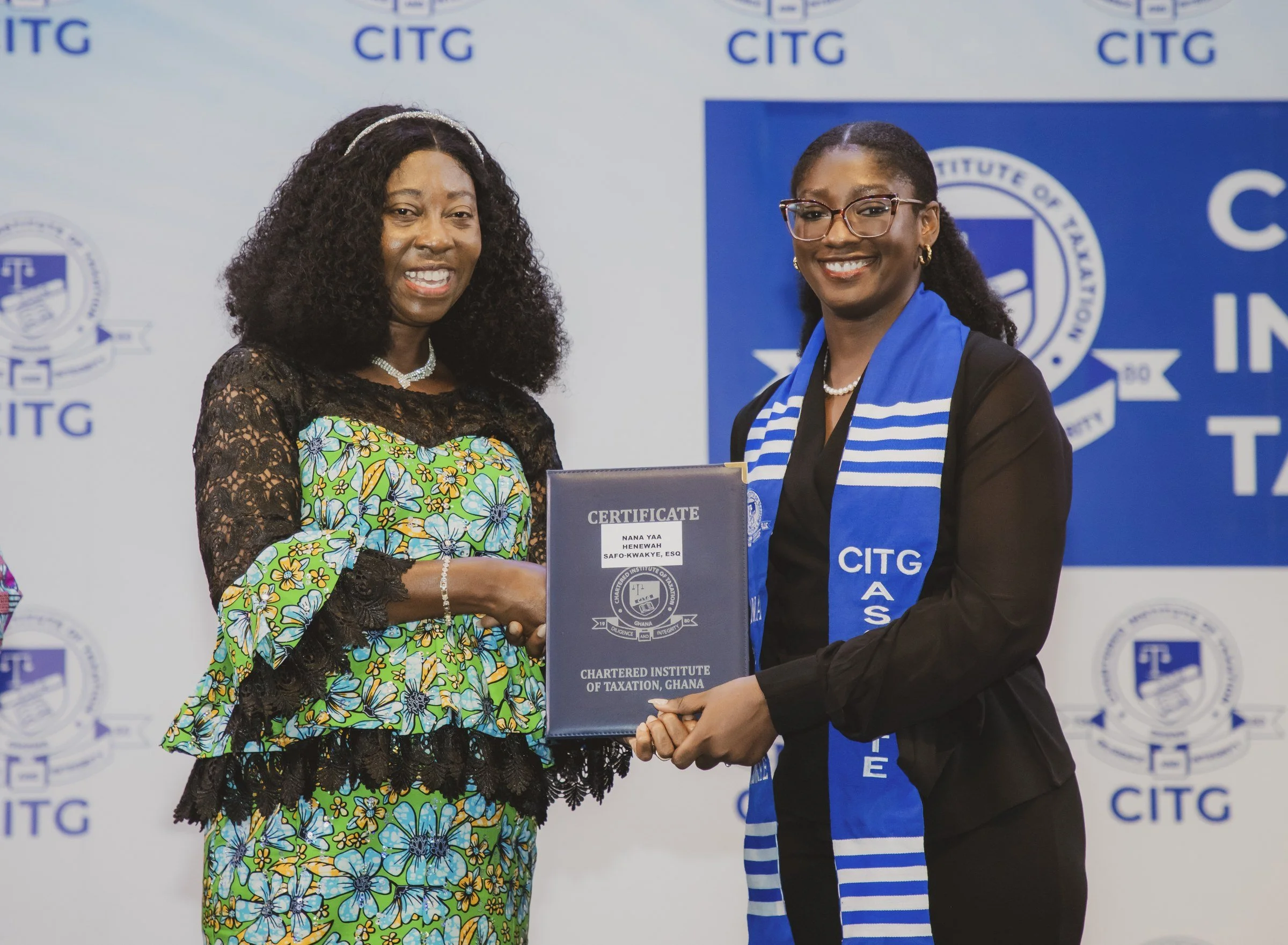 Graduate in a blue CITG stole receiving a certificate folder from a woman in a patterned dress, CITG graduation, May 2026.