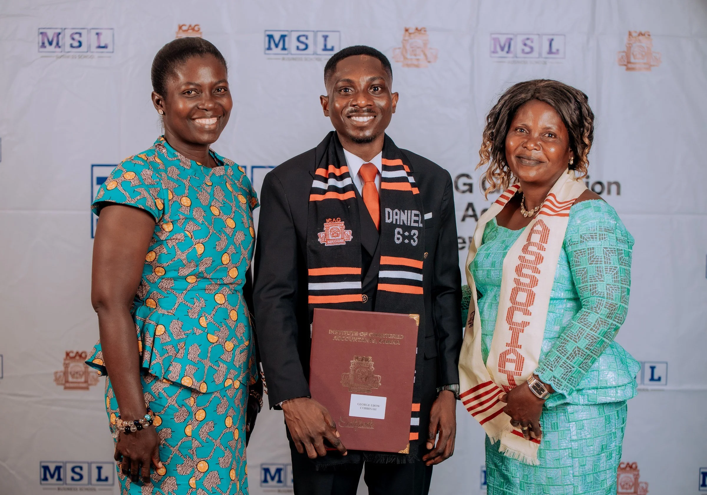 Graduate holding a certificate folder while posing with two supporters, ICAG graduation, September 2025.