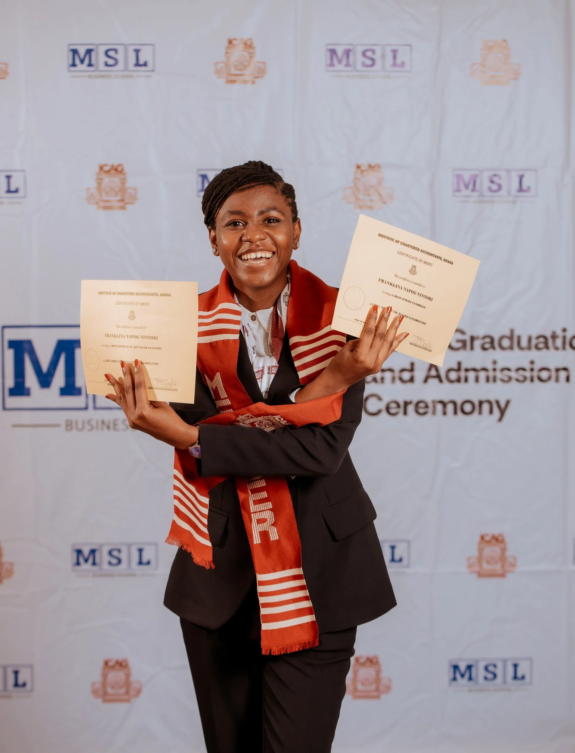 Graduate in a red ICAG stole celebrating with two certificates, ICAG graduation, September 2025.