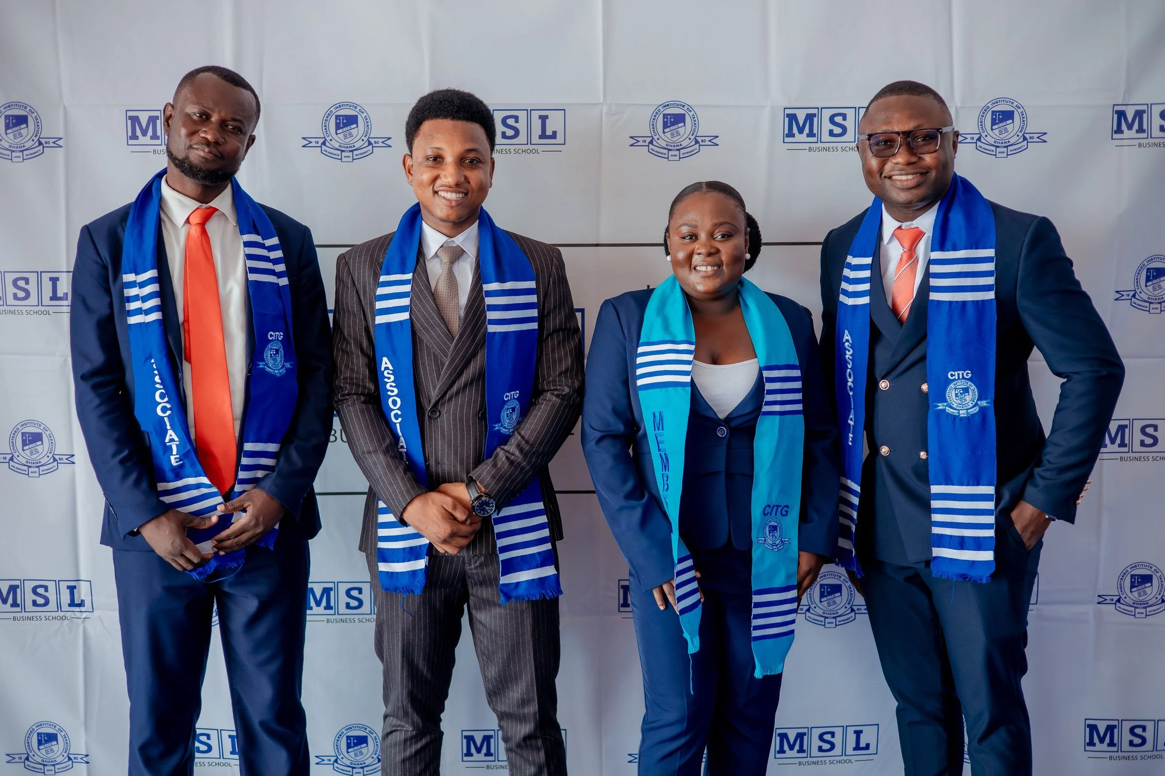 Four graduates wearing blue CITG stoles posing together at the MSL backdrop, CITG graduation, December 2025.
