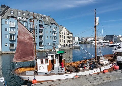 sfhs-gammel båt med rødt seil langs bryggen i Ålesund.jpg
