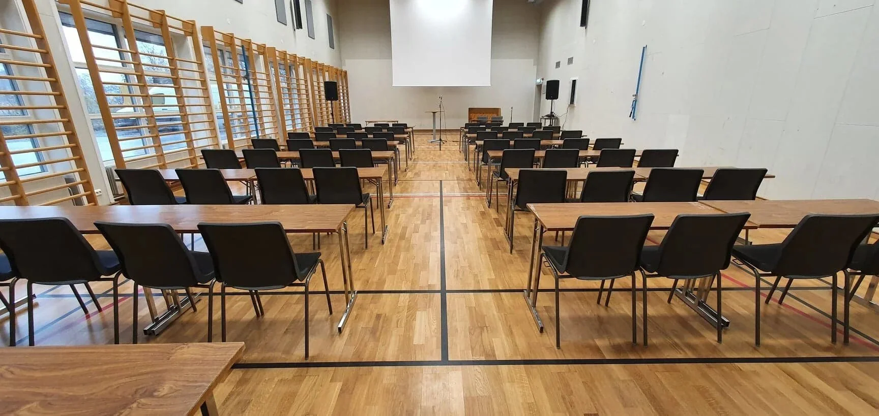 sfhs-gymsal satt opp som klasserom med rekker av bord og stoler.jpg