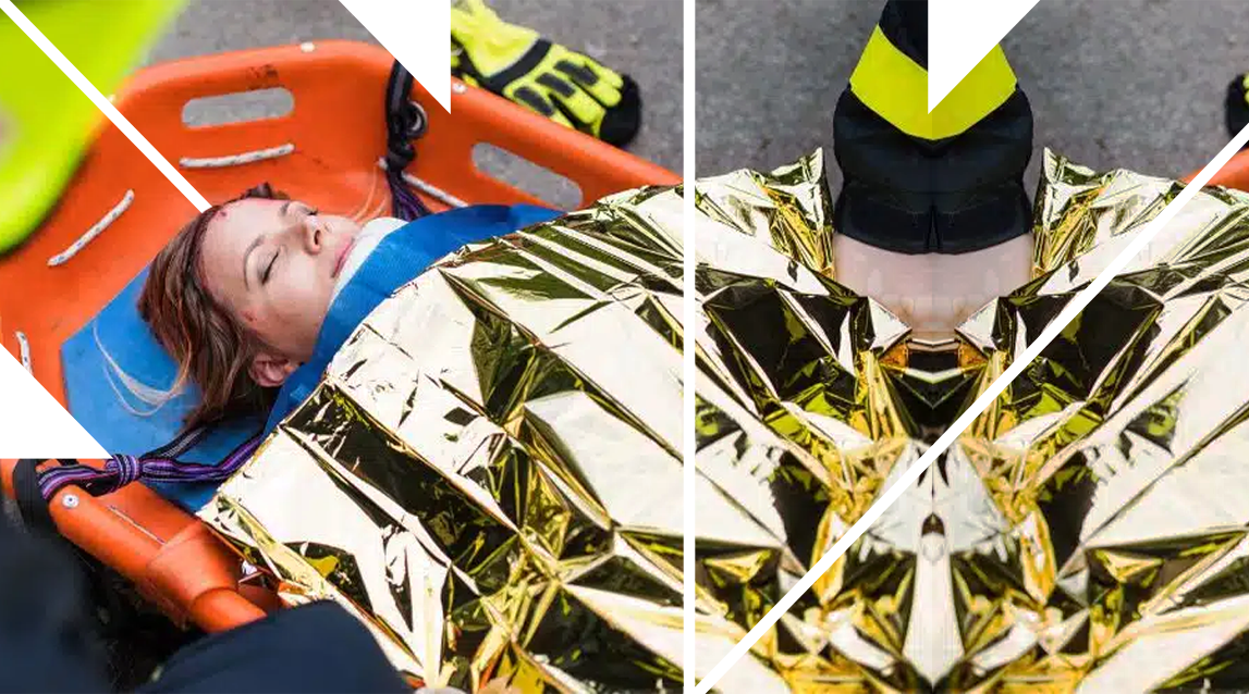 Paramedics attending to a woman on a stretcher wrapped in a gold emergency blanket.