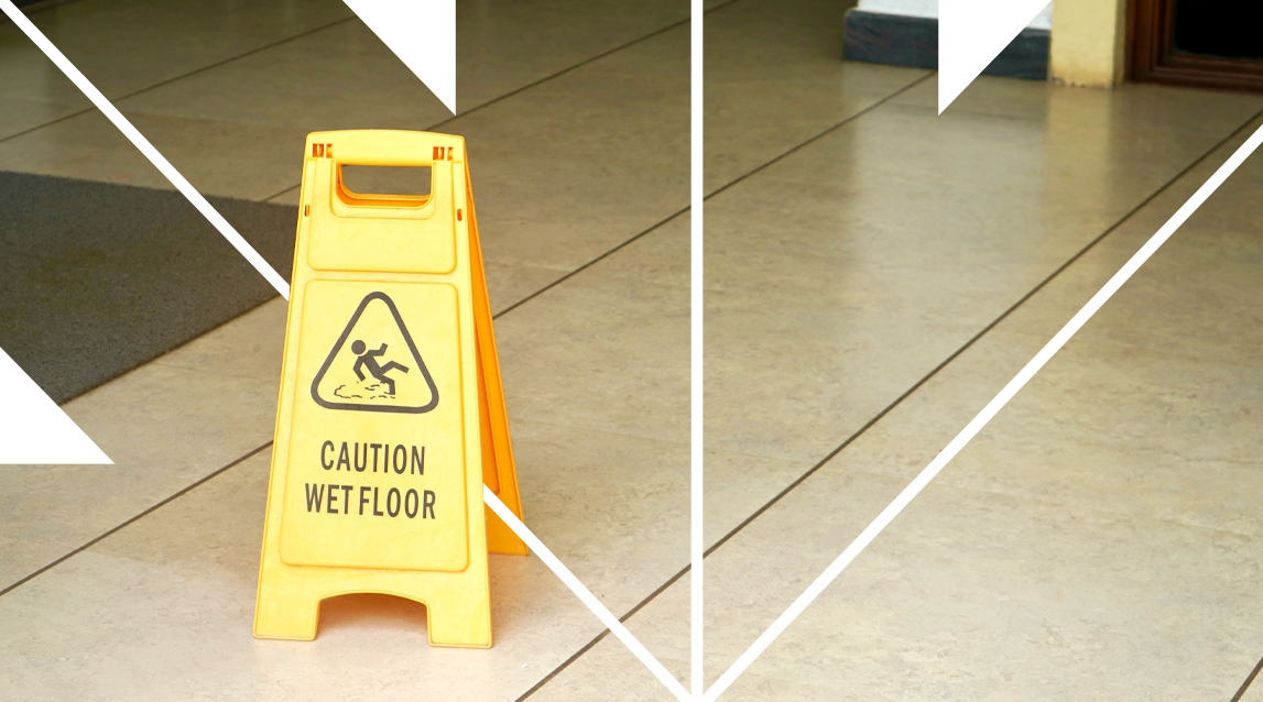 Yellow caution sign indicating wet floor in an indoor area with tiled flooring.