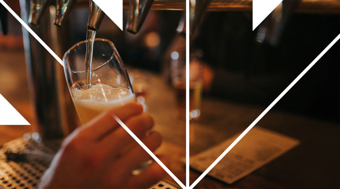A person is pouring a draft beer into a glass at a bar, with a menu and other glasses visible on the counter.