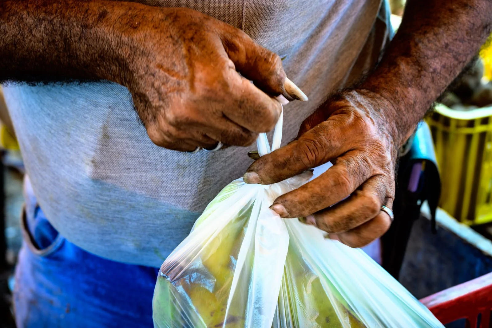 COLOMBIA 2023. Vendor at the Mercado Público de San Luis, Cúcuta.

20 December 2023. Mercado Público de San Luis, Cúcuta, Norte de Santander, Colombia. The weathered hands of a produce vendor tie a knot in a bag of groceries at one of the city's main