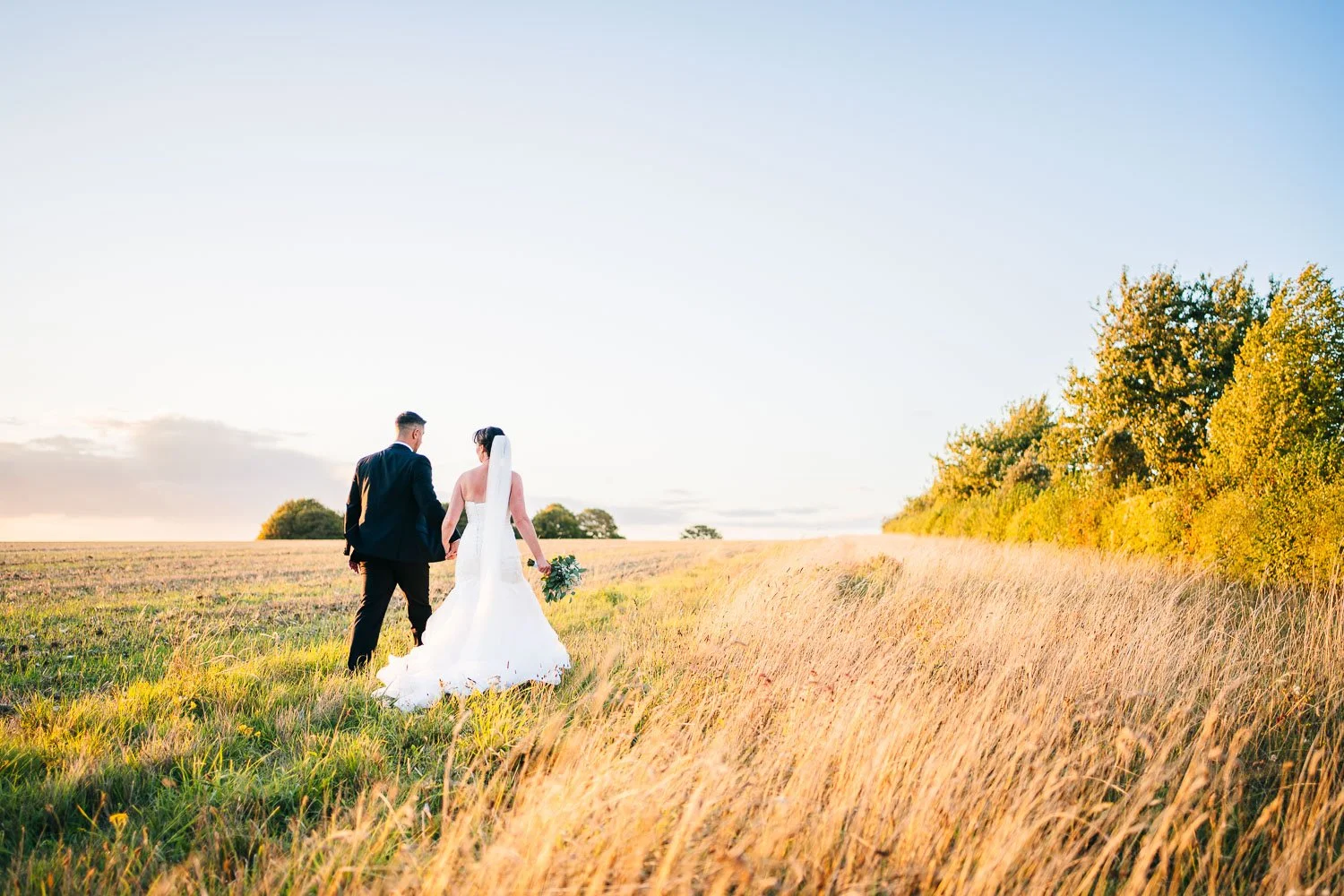 clock-barn-wedding-couple-walking-at-golden-hour-candid.jpg