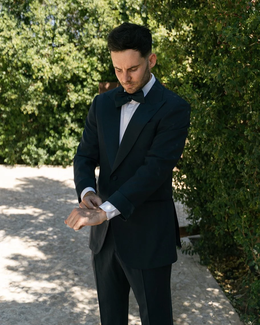 Timo Burbridge in a midnight blue peak lapel tuxedo, adjusting his cuff