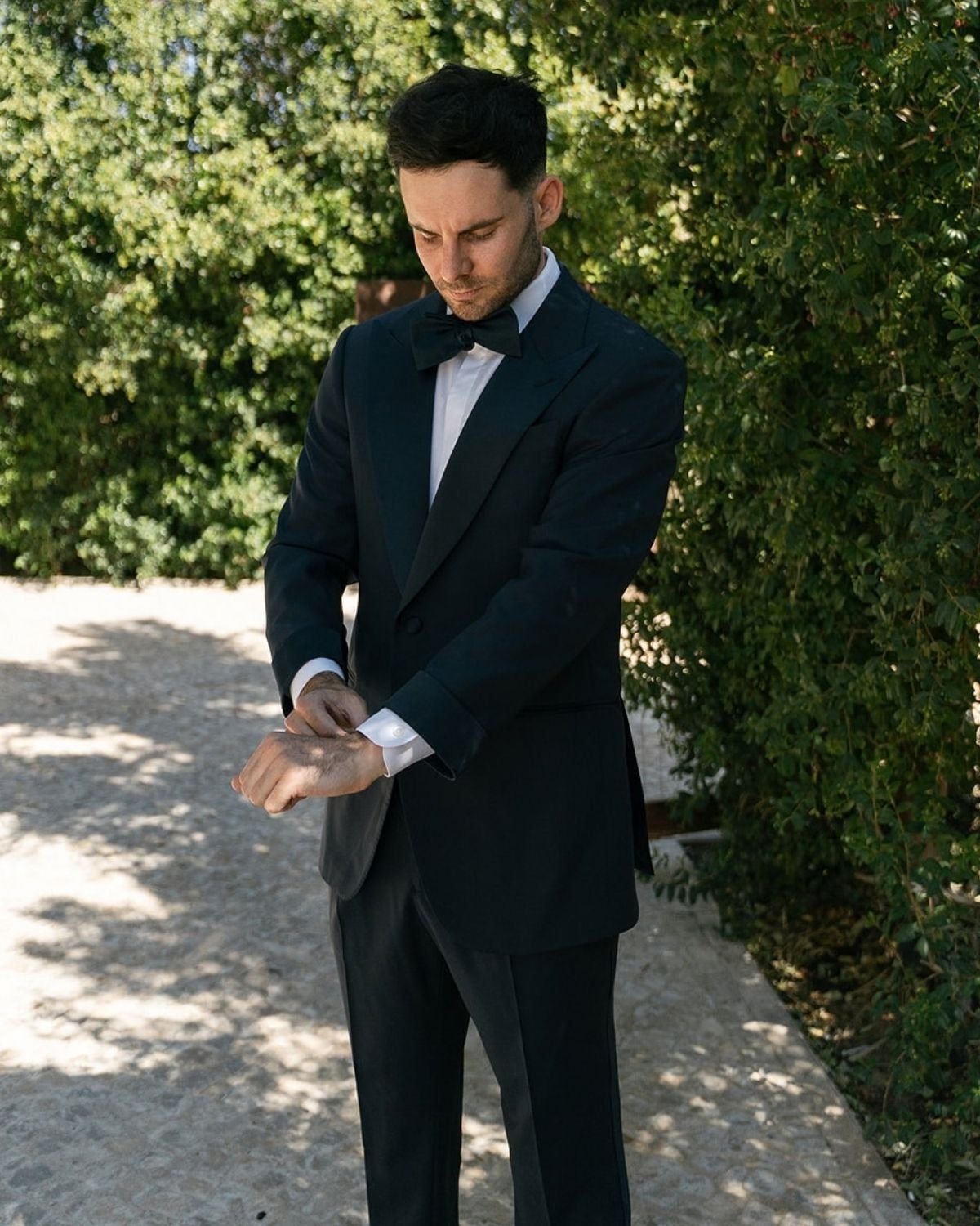 Timo Burbridge in a midnight blue peak lapel tuxedo, adjusting his cuff