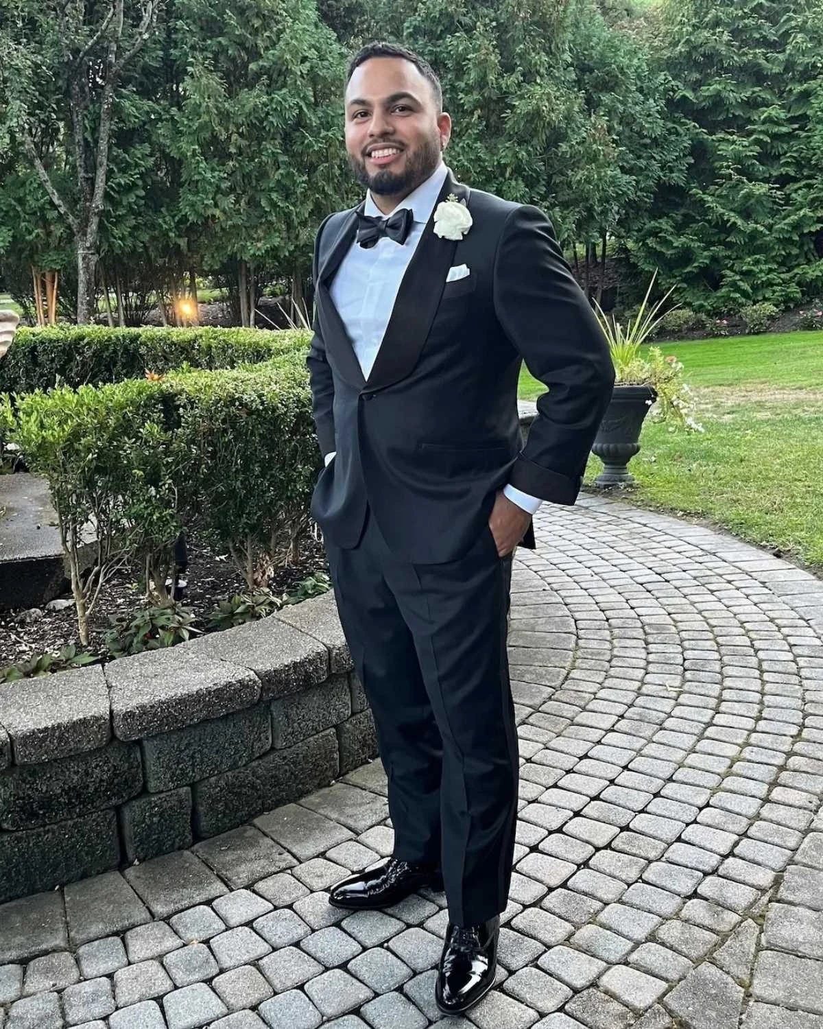 Jeff Ramirez in a black shawl collar tuxedo in a garden