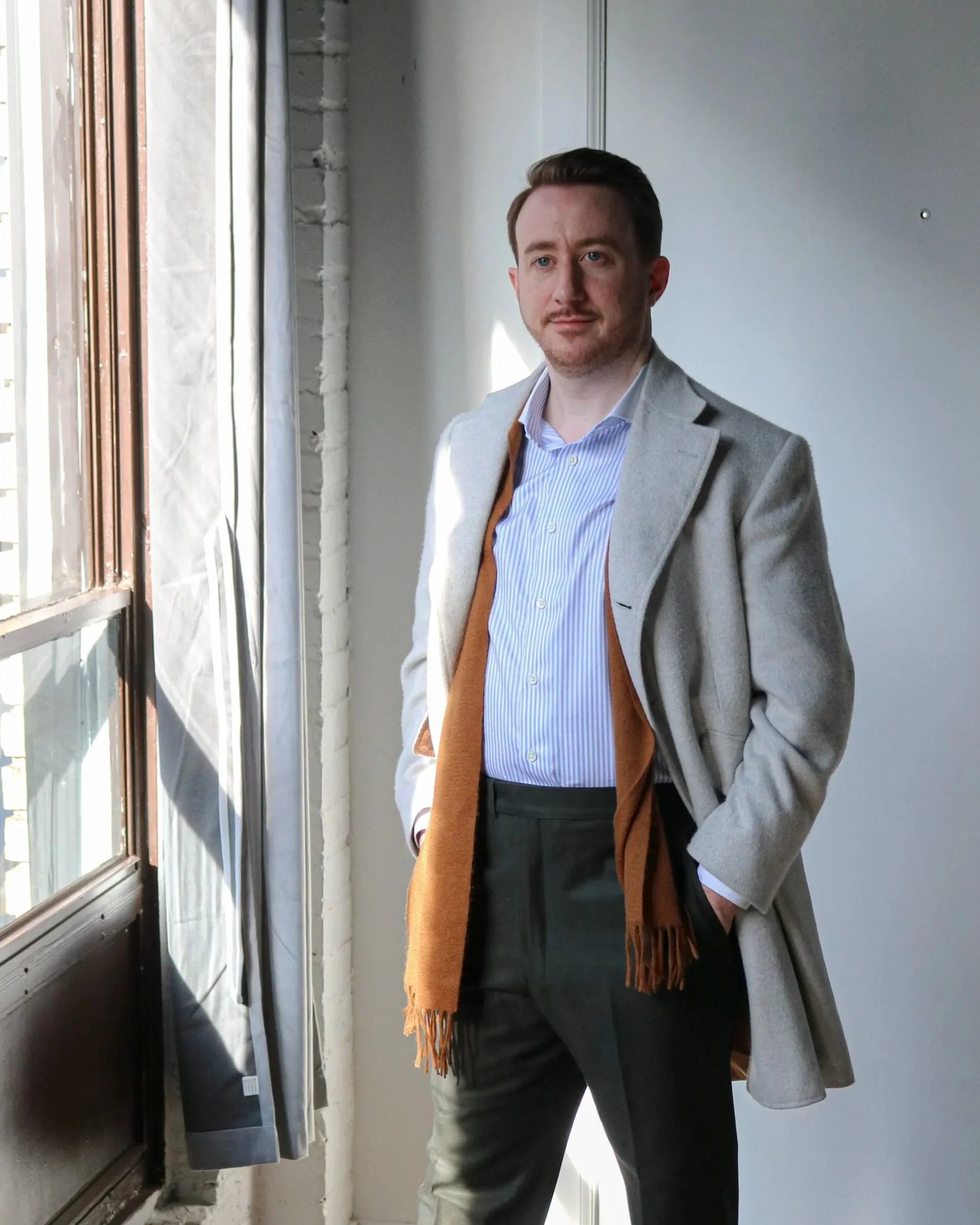 Client wearing a made to measure dress shirt, trousers and light grey cashmere overvcoat