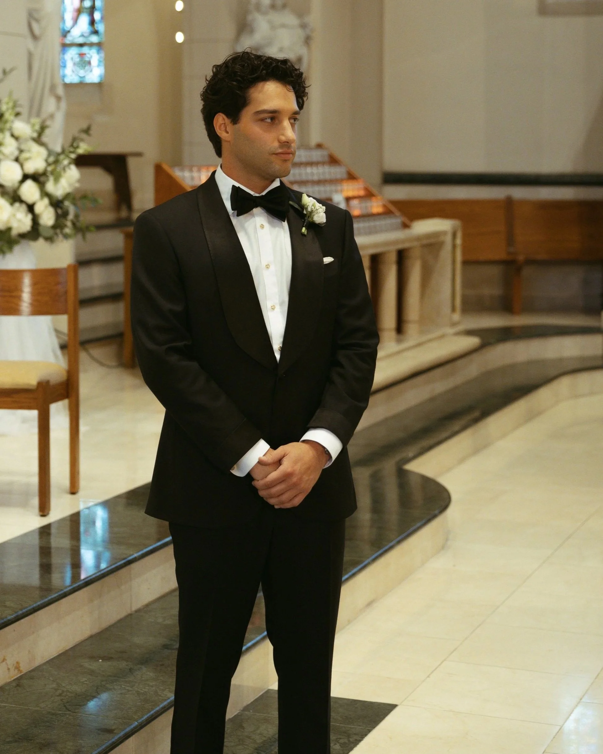 Matt Oristanio in a black shawl collar tuxedo at the altar