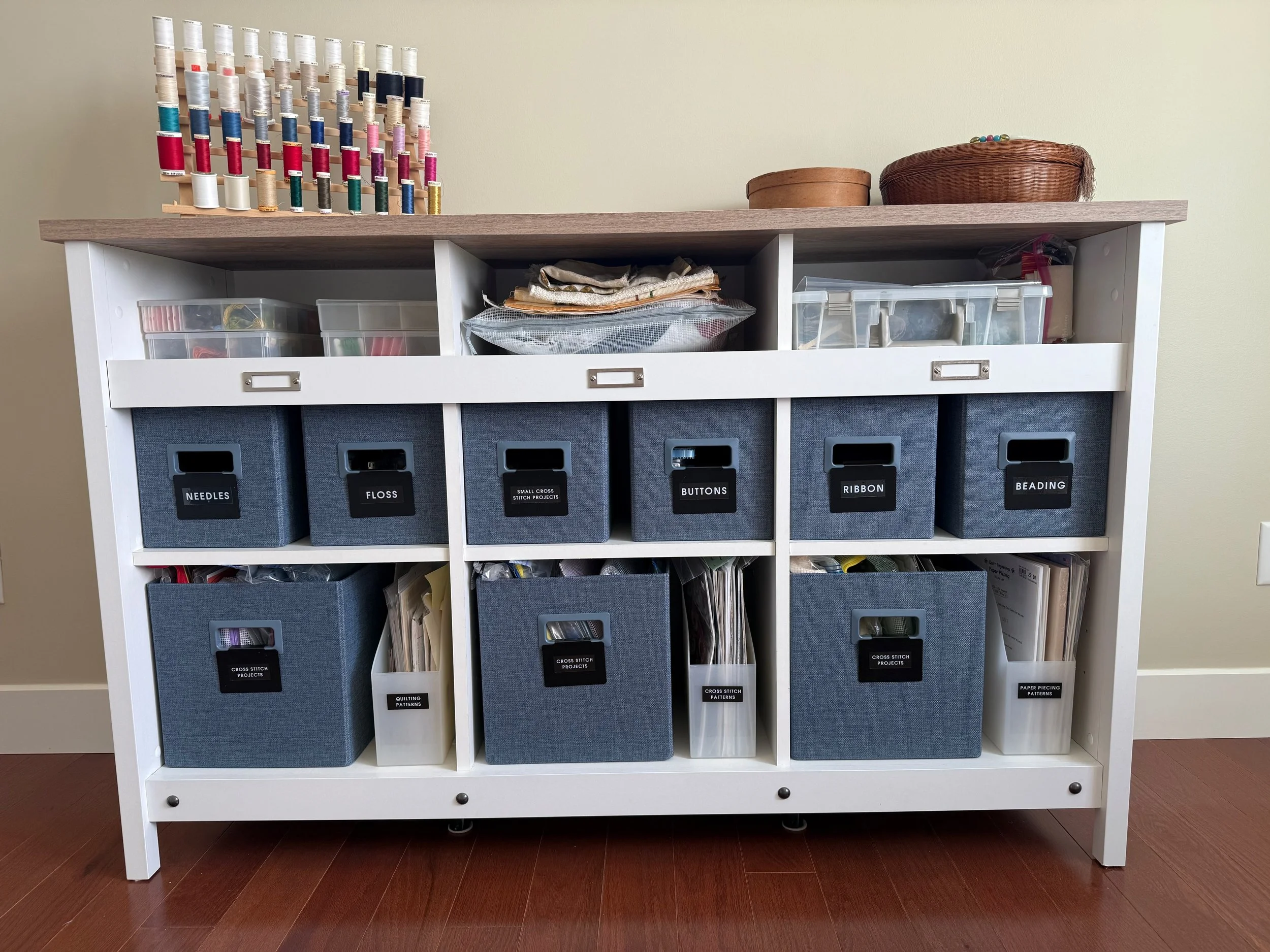 Separate bins for needles, floss, buttons, ribbon, and beading supplies, with additional storage for cross-stitch projects and patterns.