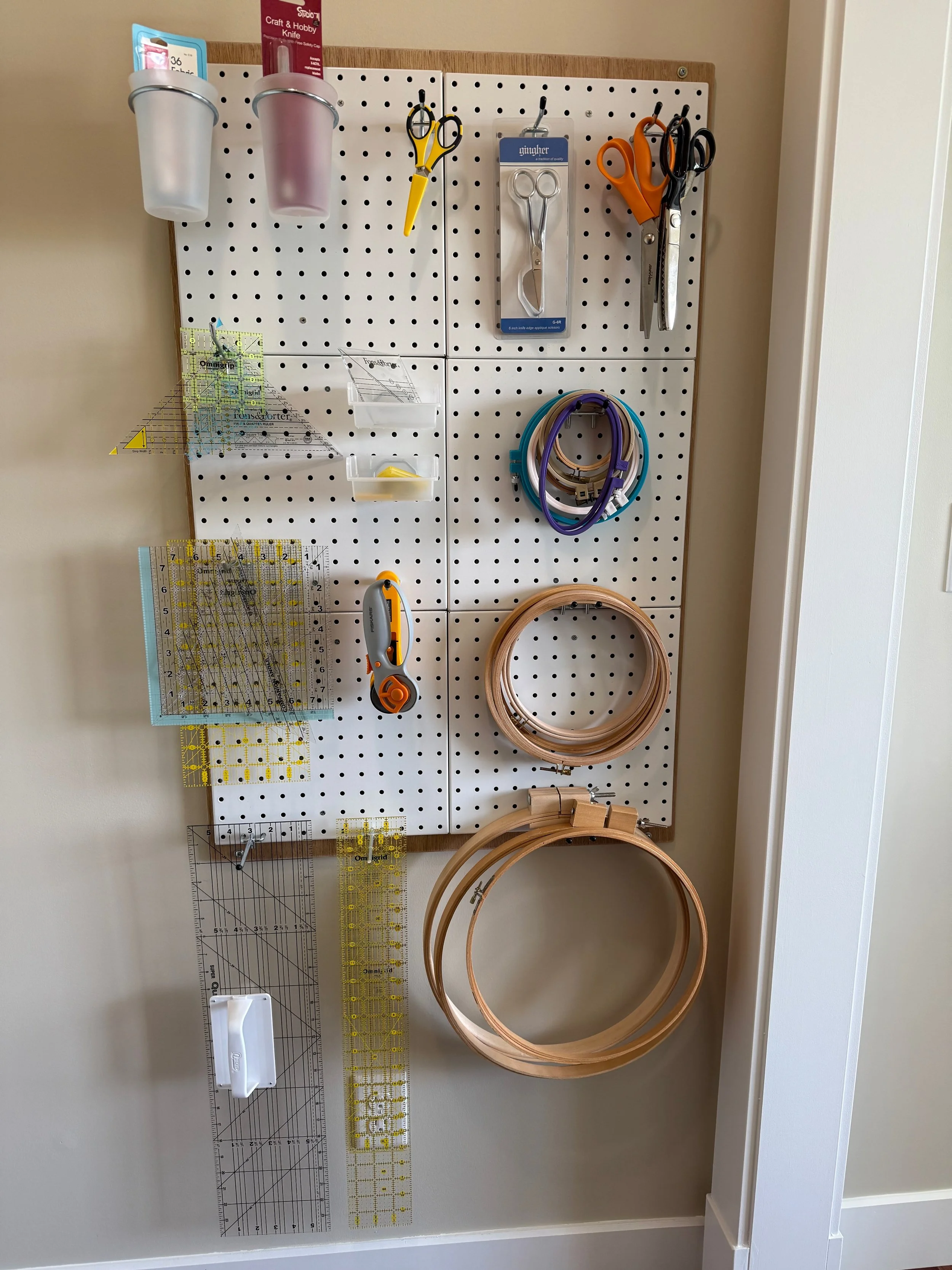 Wall storage keeps scissors, quilting rulers, and embroidery hoops visible without taking up the work surface.