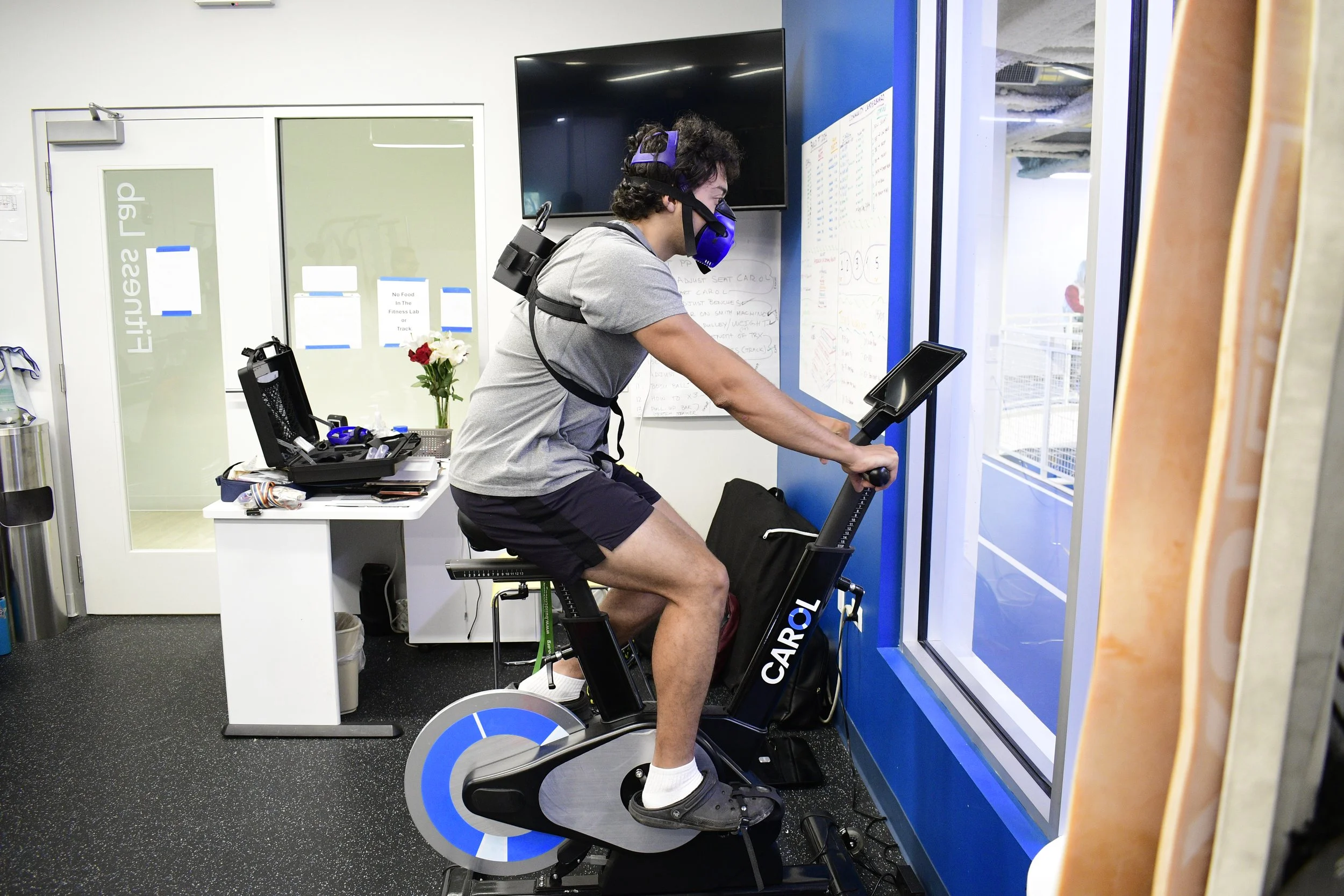 Person wearing a breathing apparatus exercising on a stationary bike in a fitness lab.