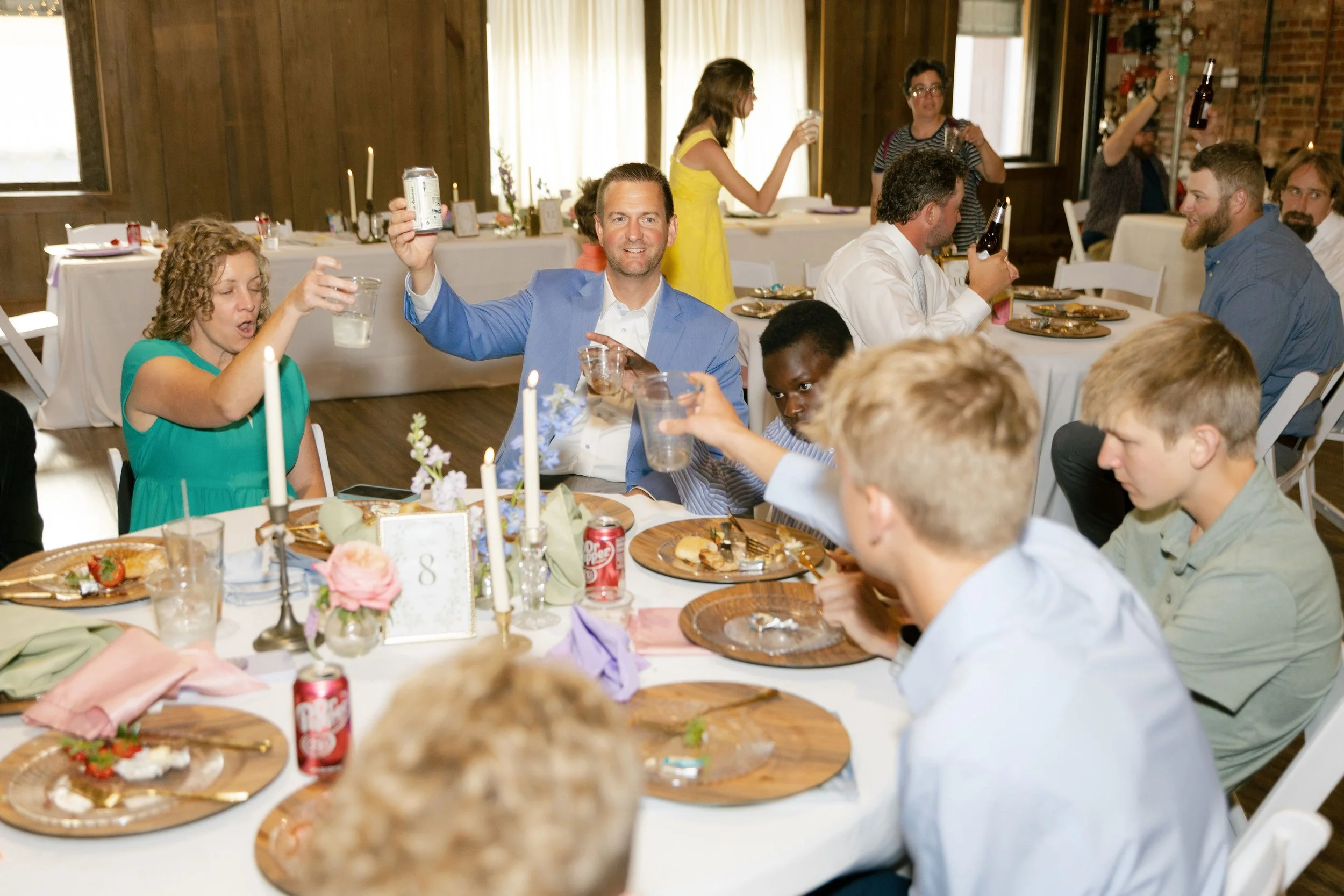 People celebrating at a corporate event, raising glasses in a toast around a decorated table with food and drinks.