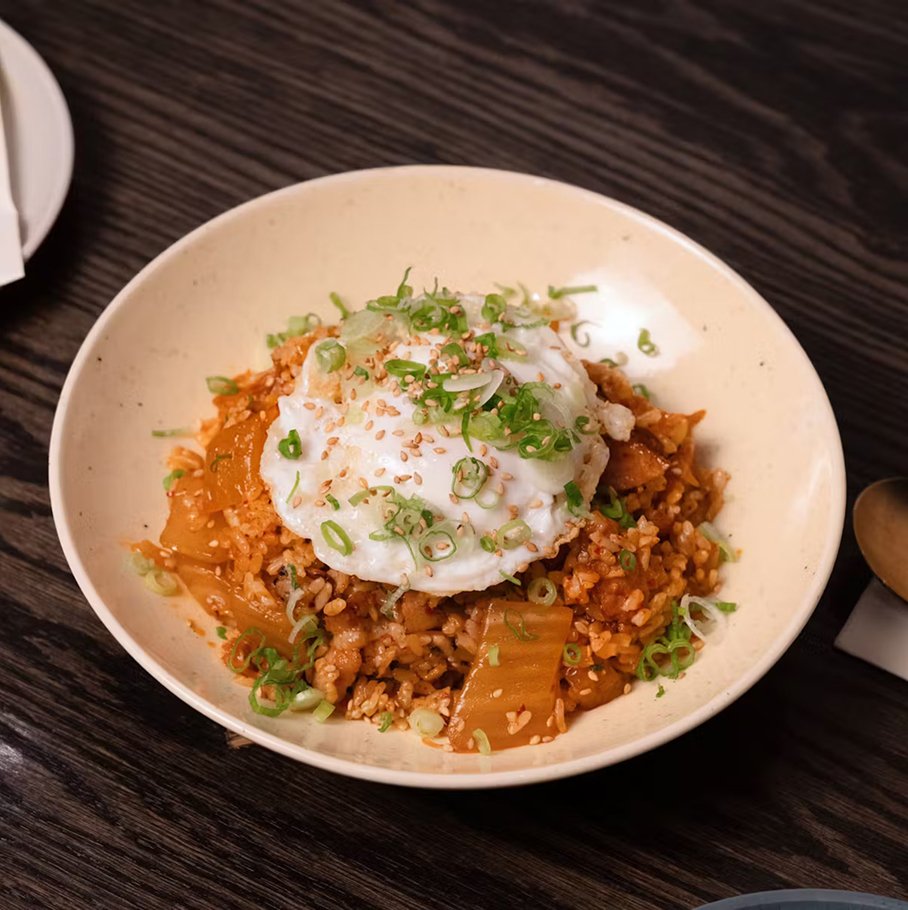 Kimchi fried rice — kimchi fried rice with bacon topped with a fried egg sesame seeds and scallions