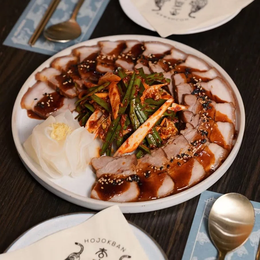 Soy-glazed bossam — slow-braised pork belly with soy glaze, garlic, ginger, chive salad, and radish ssam