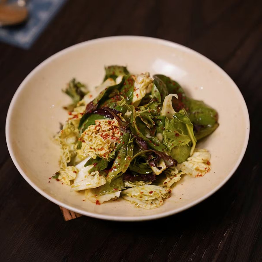Fresh cilantro kimchi made with napa cabbage and mixed greens, lightly dressed and served in a ceramic bowl