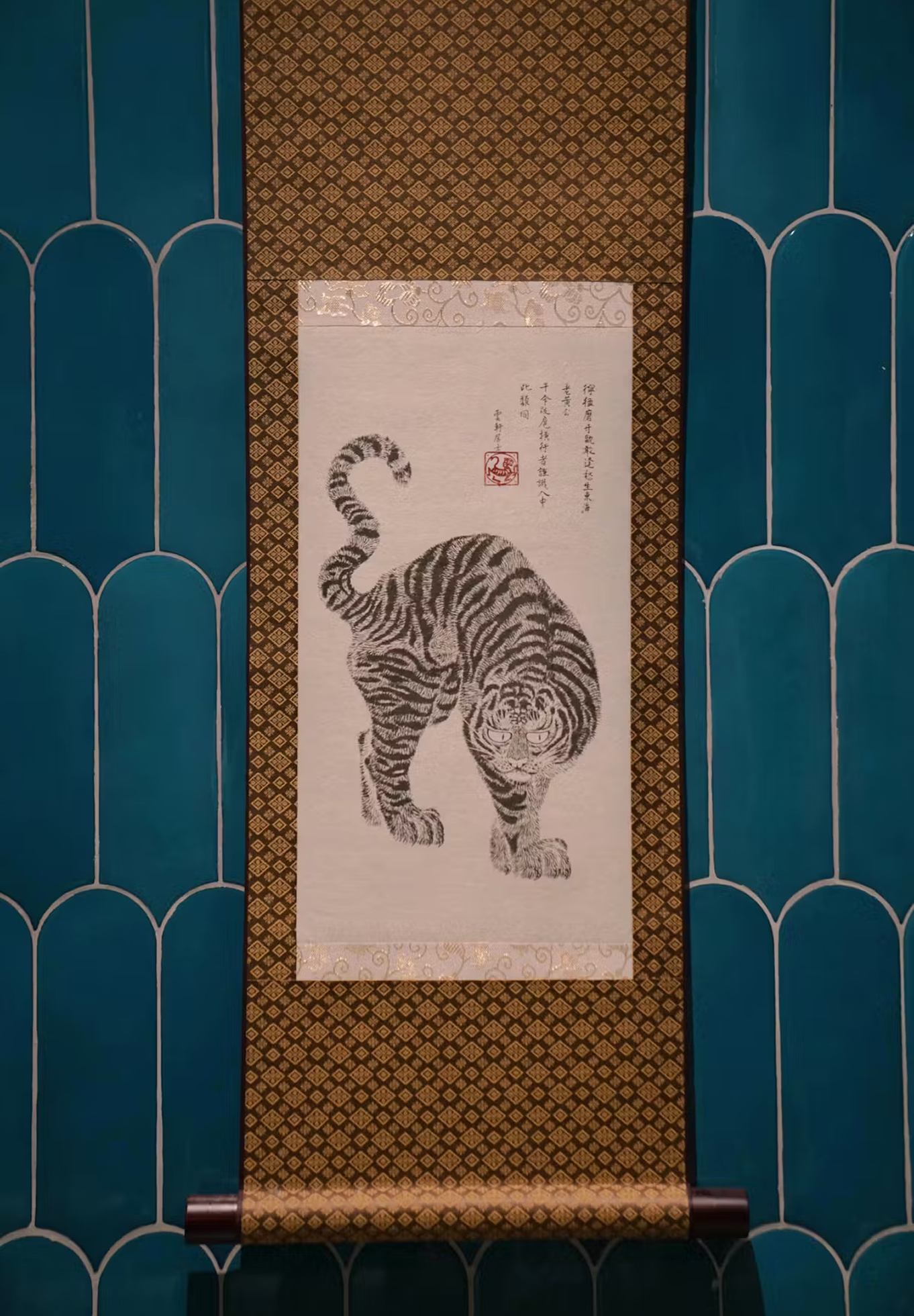 Traditional Korean tiger scroll painting hanging on a blue tiled wall.