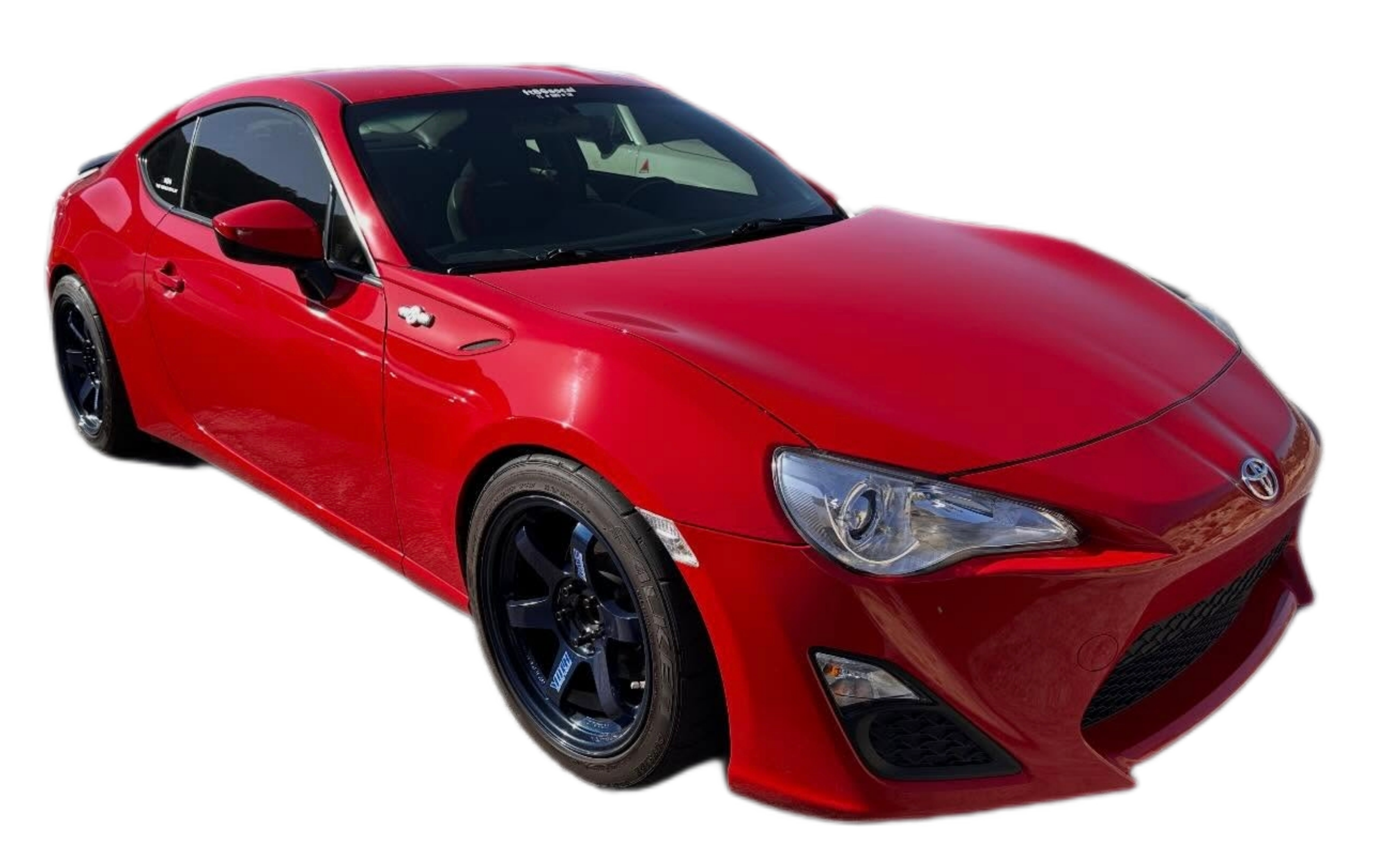 Red sports car with black wheels, parked outdoors, with a sleek and aerodynamic design.