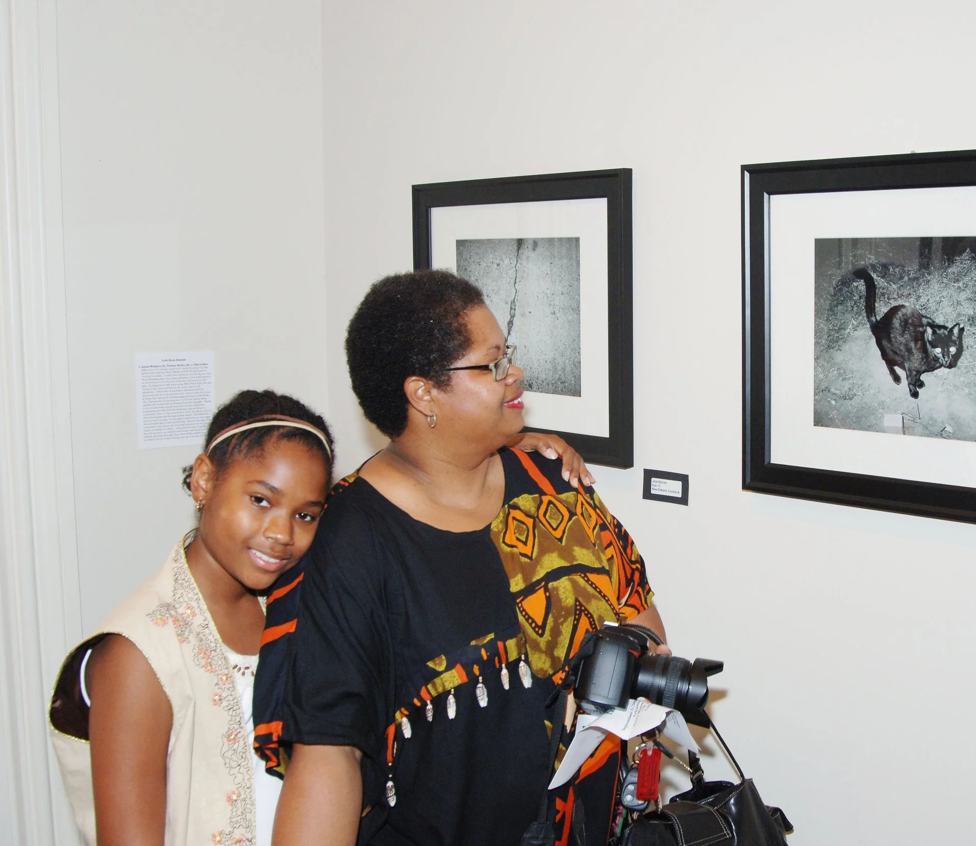 A woman and a girl at an art gallery, looking at black and white photographs of animals on the wall.