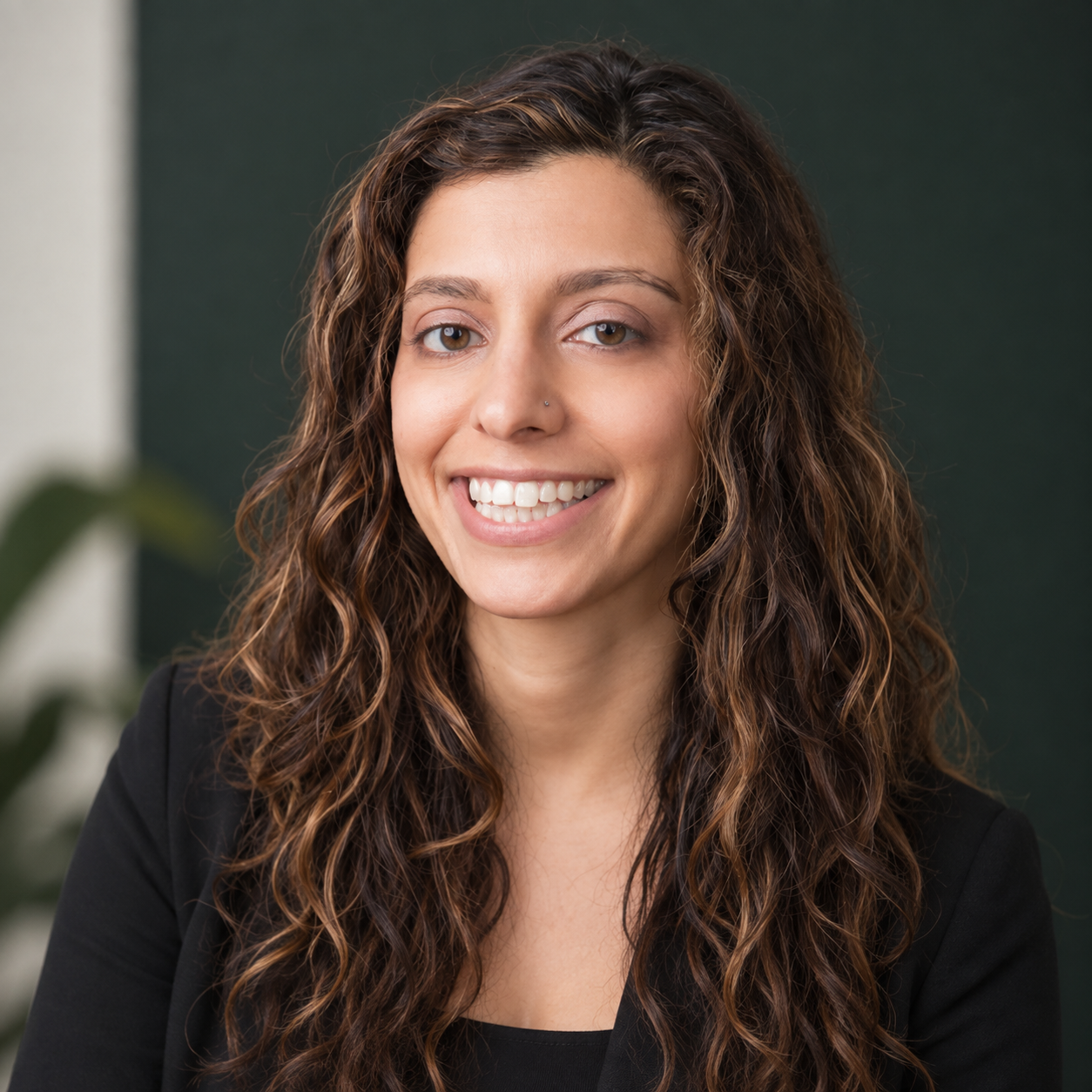 Headshot of a woman with long brown hair wearing a black suit