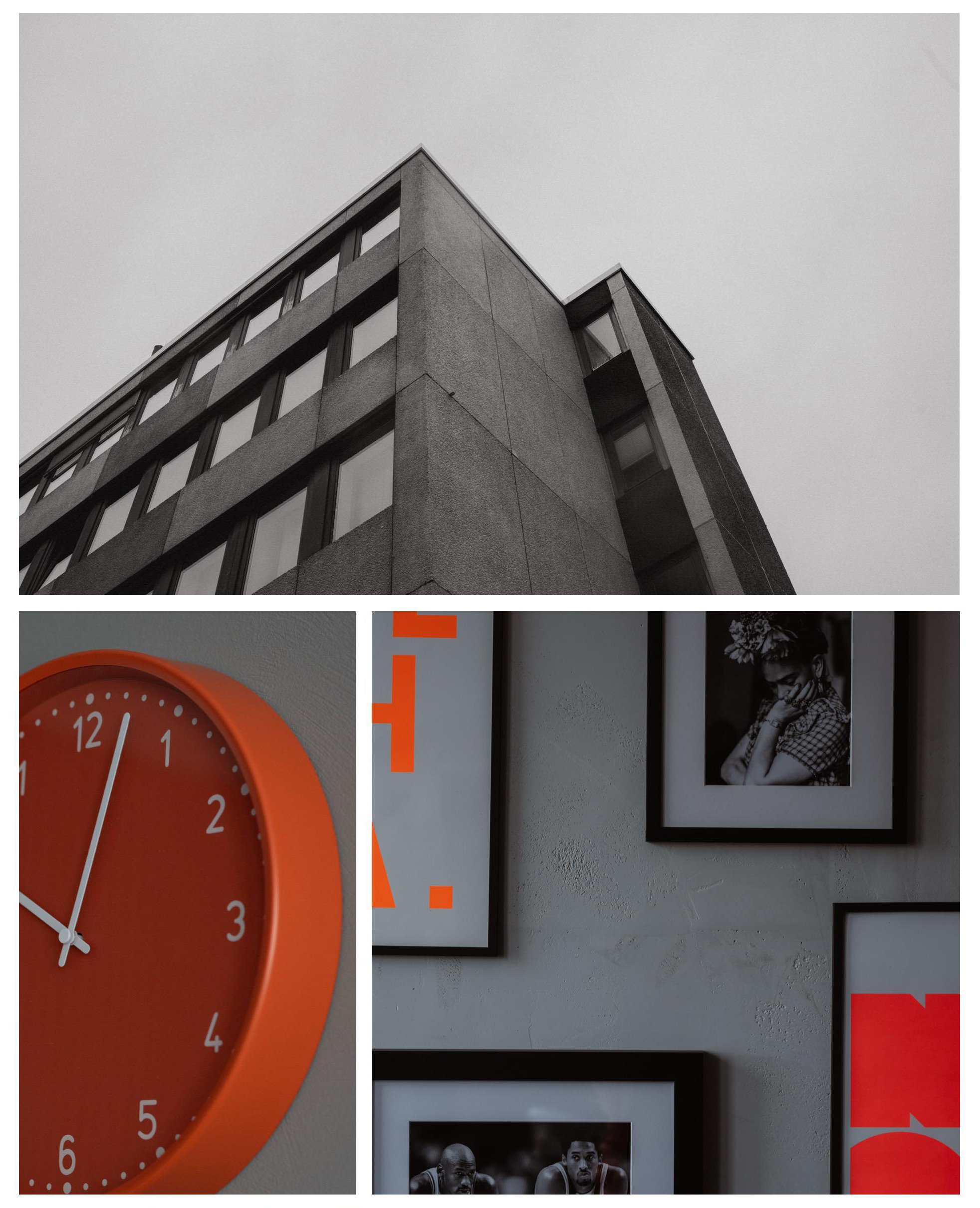 Schwarz-weißfoto eines modernistischen Gebäudes mit klaren Linien und großen Fenstern, eine orangefarbene Wanduhr mit weißen Ziffern und Zeigern, und eine Wand mit mehreren gerahmten Schwarz-Weiß-Fotografien.