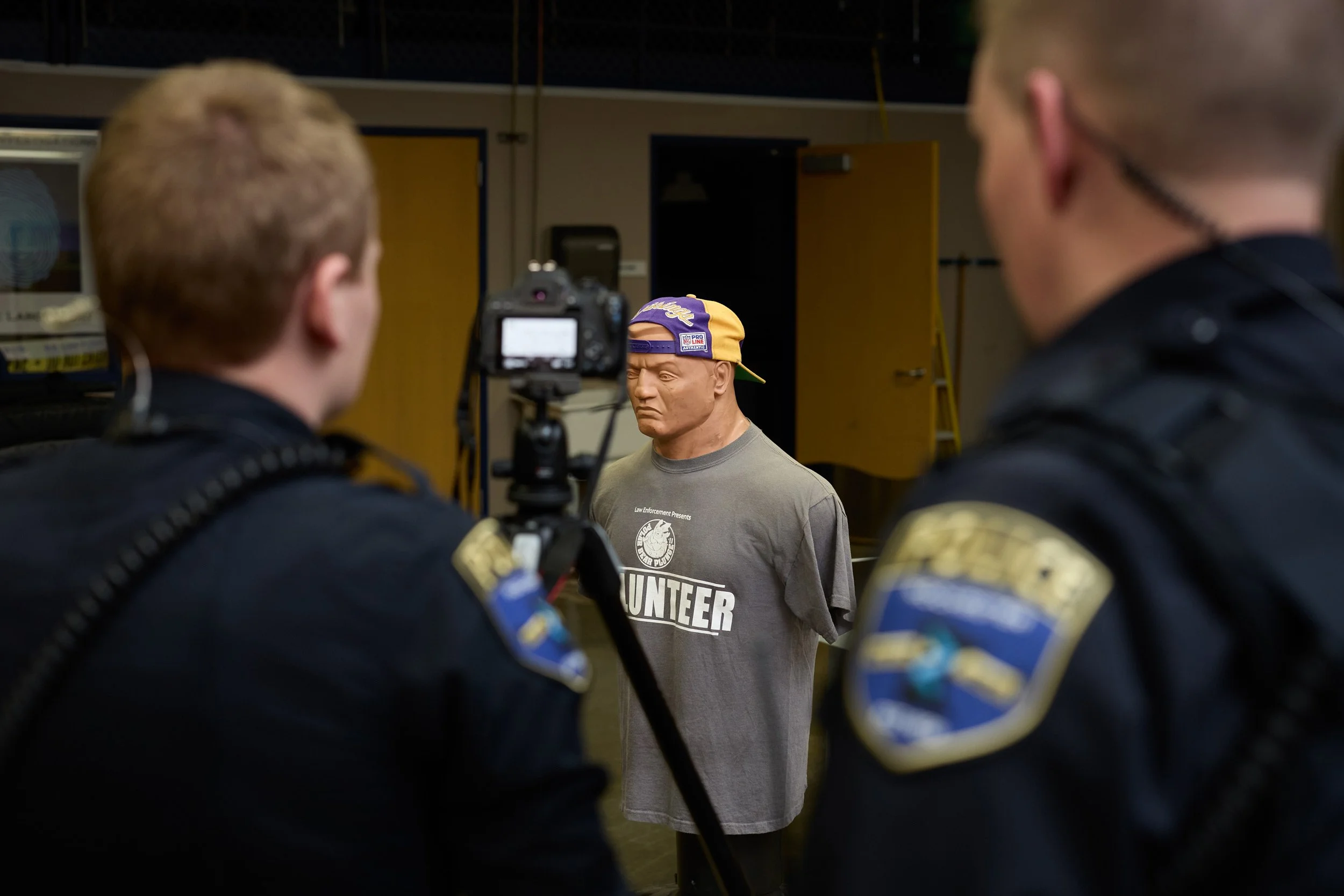 Bob the training mannequin in sharp focus while two Rochester police officers practice low-light photography techniques in the background, RCTC crime scene photography class